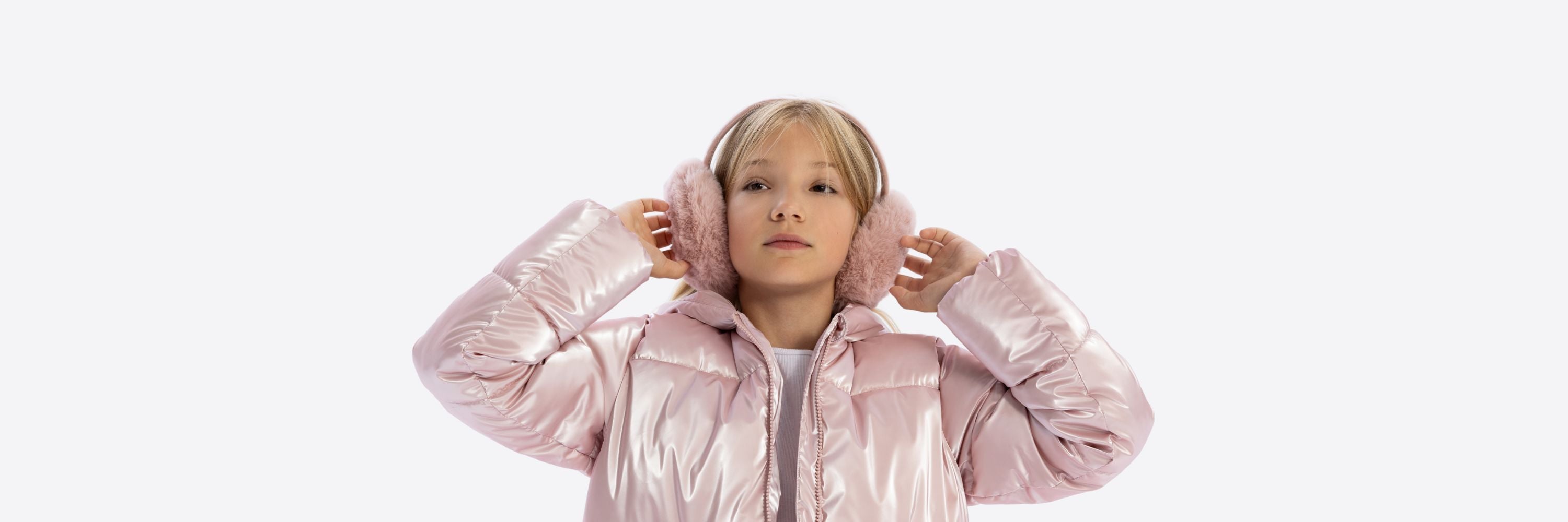 A young girl wearing a shiny pink puffer jacket and soft pink earmuffs, posed against a white background.