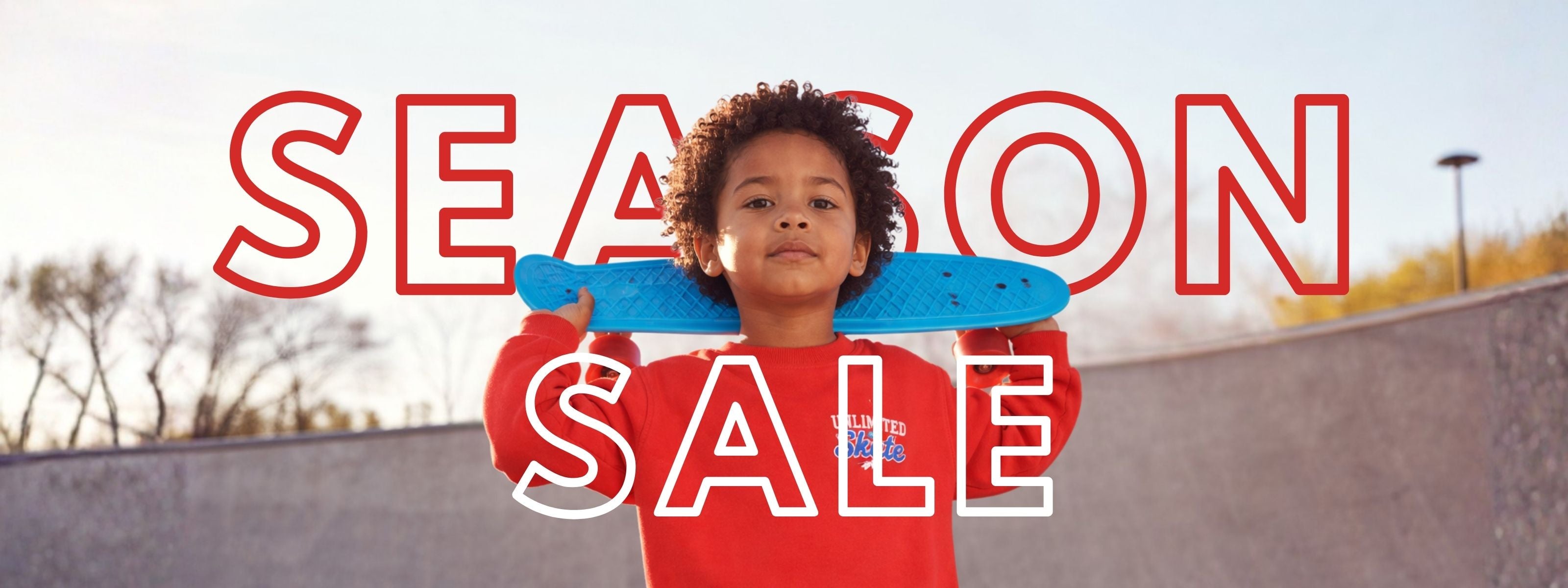 A BOY WITH A SKATEBOARD IN A SKATE PARK, WEARING A RED SWEATSHIRT. SLOGAN: SEASON SALE