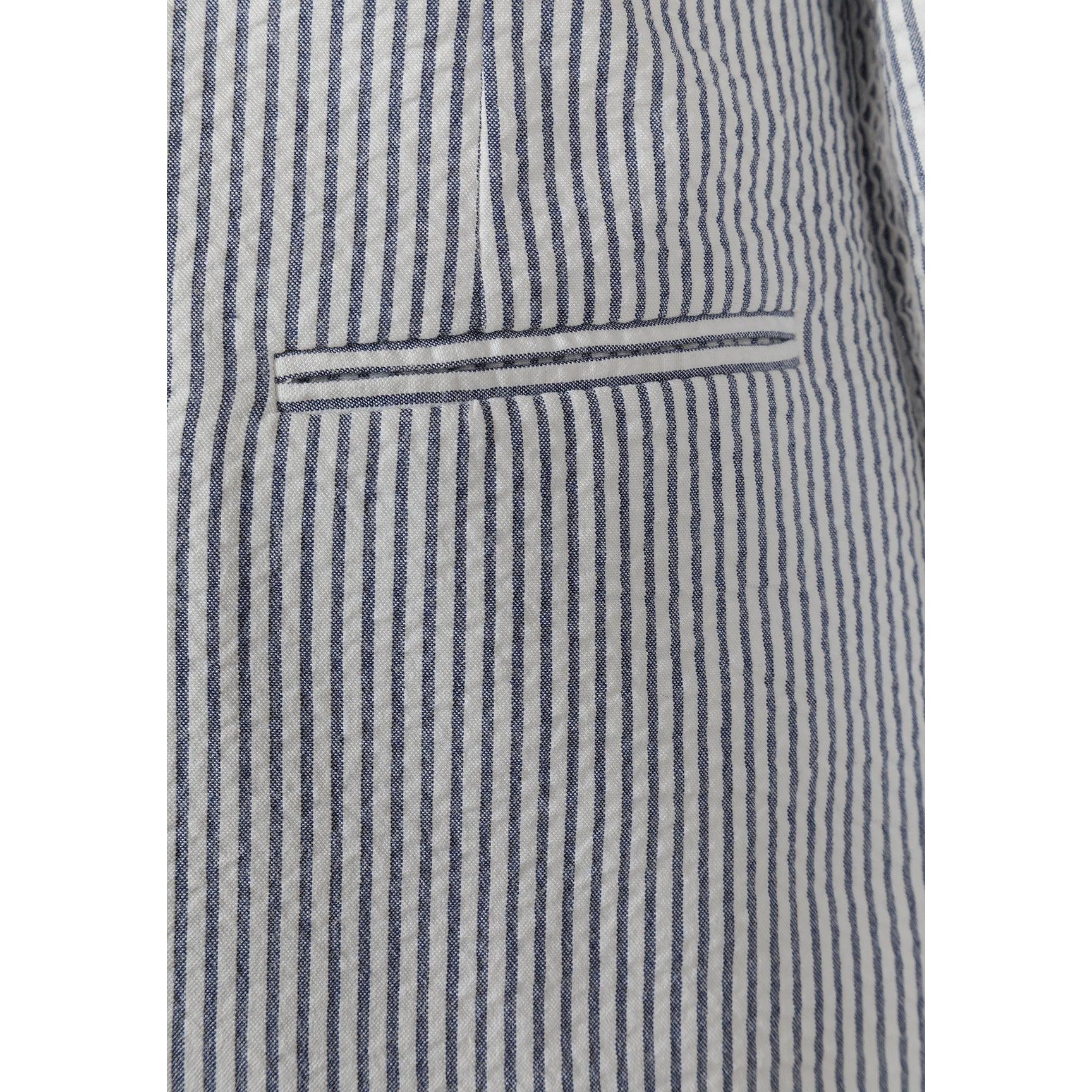 Full length front view of boy in navy striped blazer with white shirt and shorts, smiling naturally against neutral grey studio background