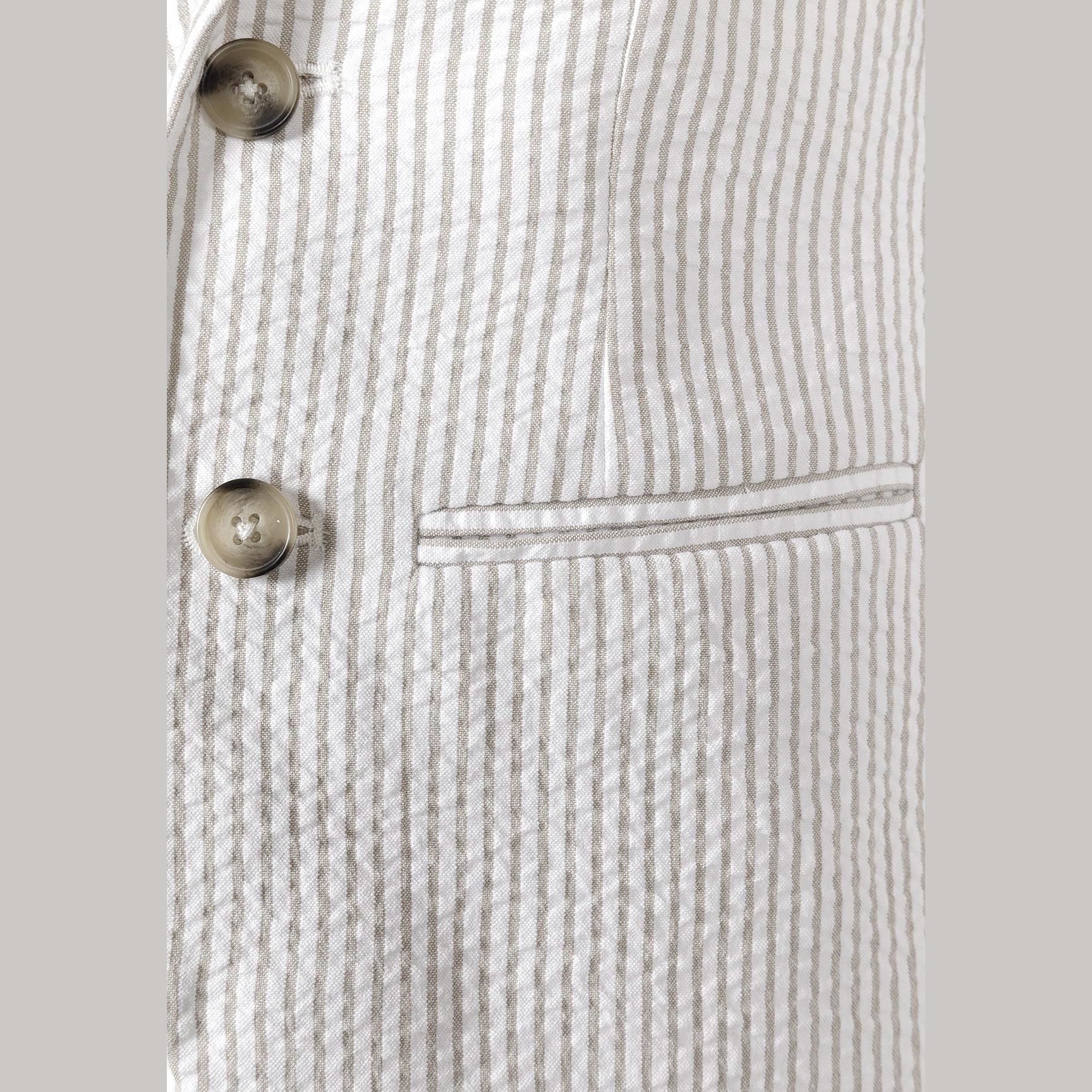 Close-up detail of stone striped cotton blazer showing two brown buttons and chest pocket on textured striped fabric