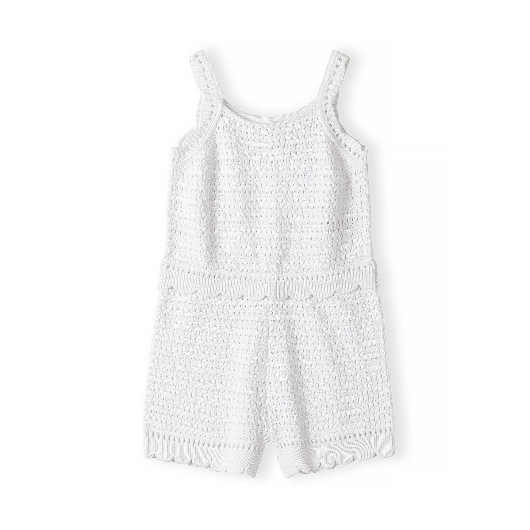 Flat lay of white pointelle knit romper showing decorative openwork pattern, wide shoulder straps, scalloped waistband and hem against white background