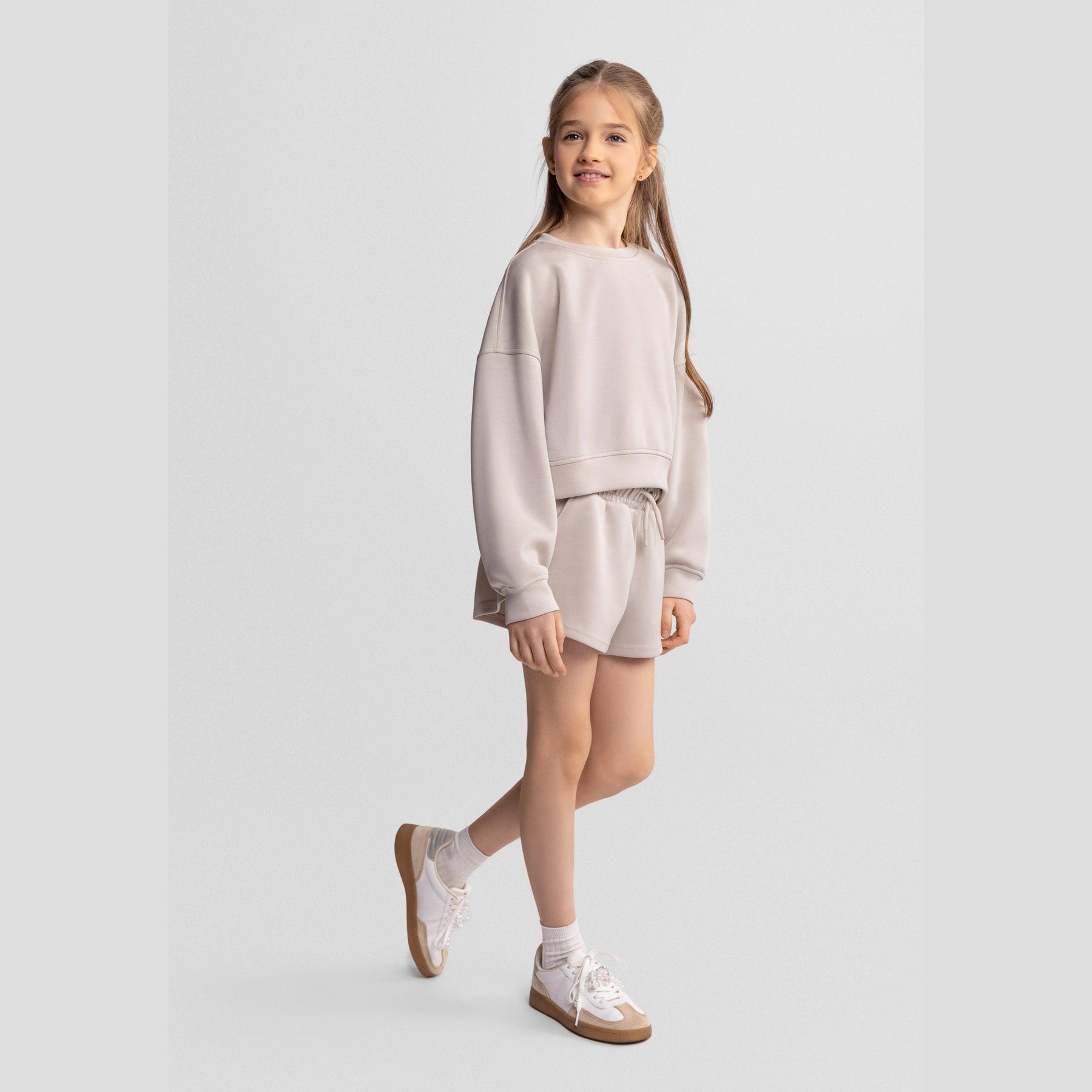 Beige sweatshirt laid flat showing relaxed crew neck design and long sleeves on white background