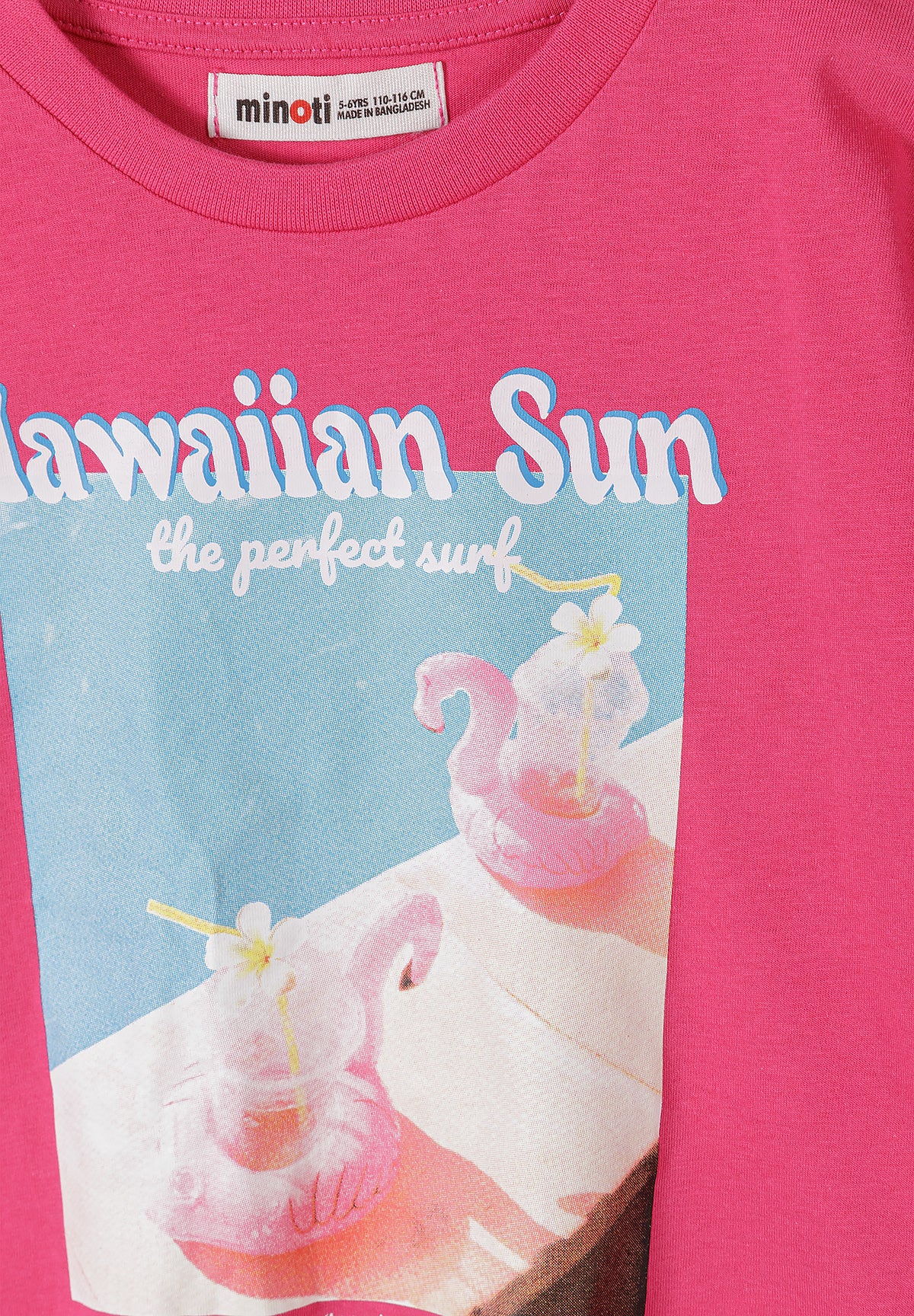 Close-up detail of hot pink t-shirt showing Minoti label at neck and Hawaiian Sun graphic print with tropical drinks, flowers and beach imagery