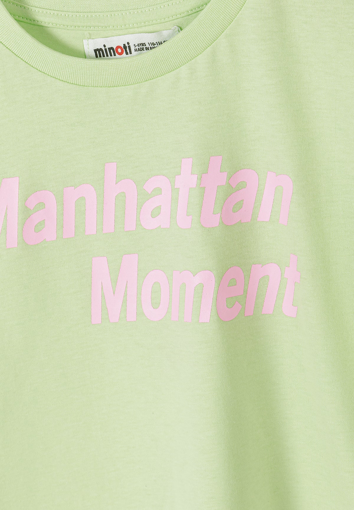 Close-up detail of pink and yellow striped t-shirt fabric showing Minoti label at neck and horizontal stripe pattern