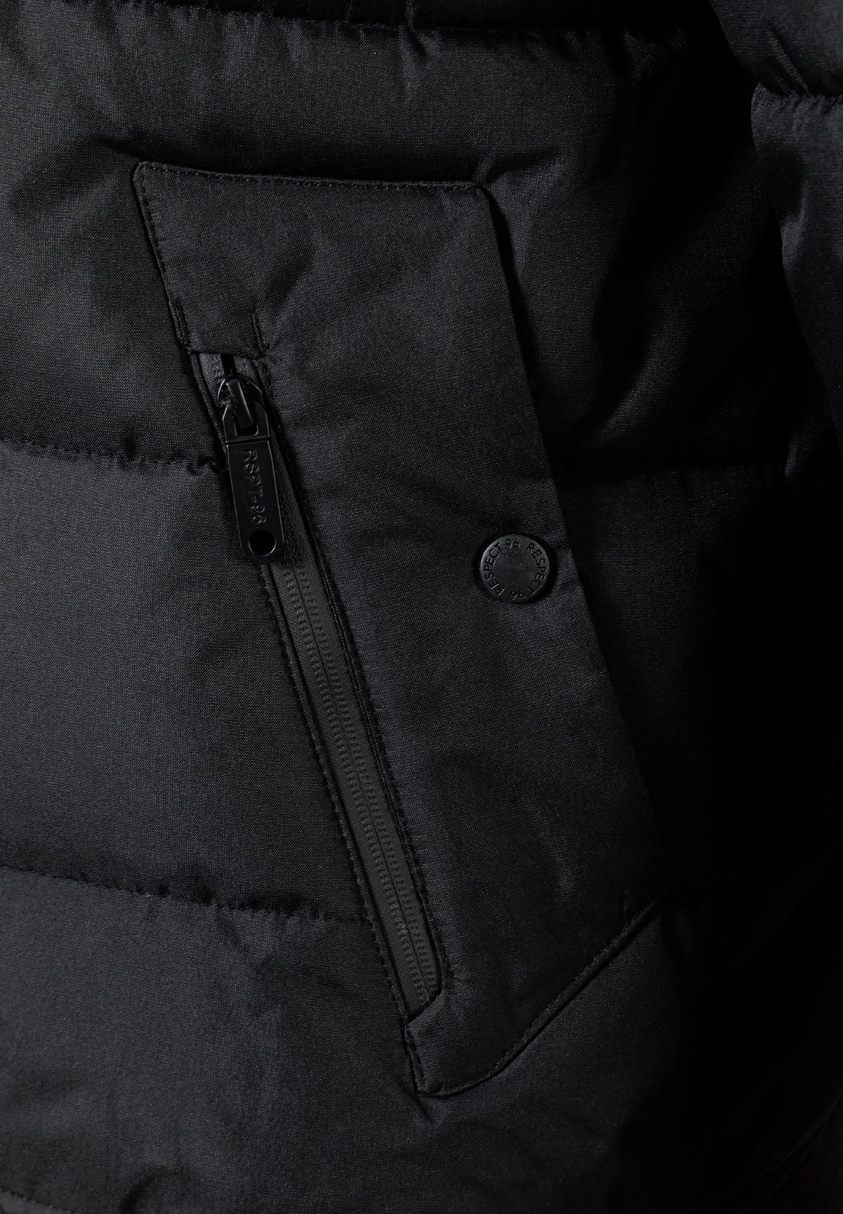 Detail of a black padded jacket showing a zip pocket and logo badge.
