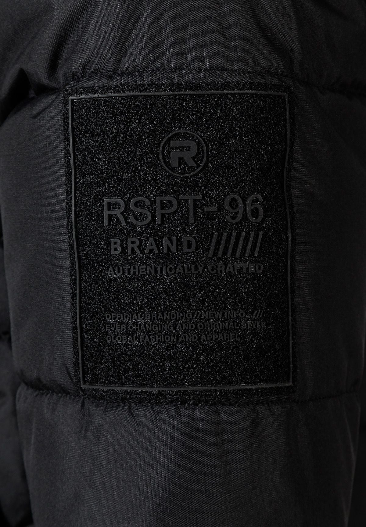 Detail of a black padded jacket with a logo badge on the sleeve.