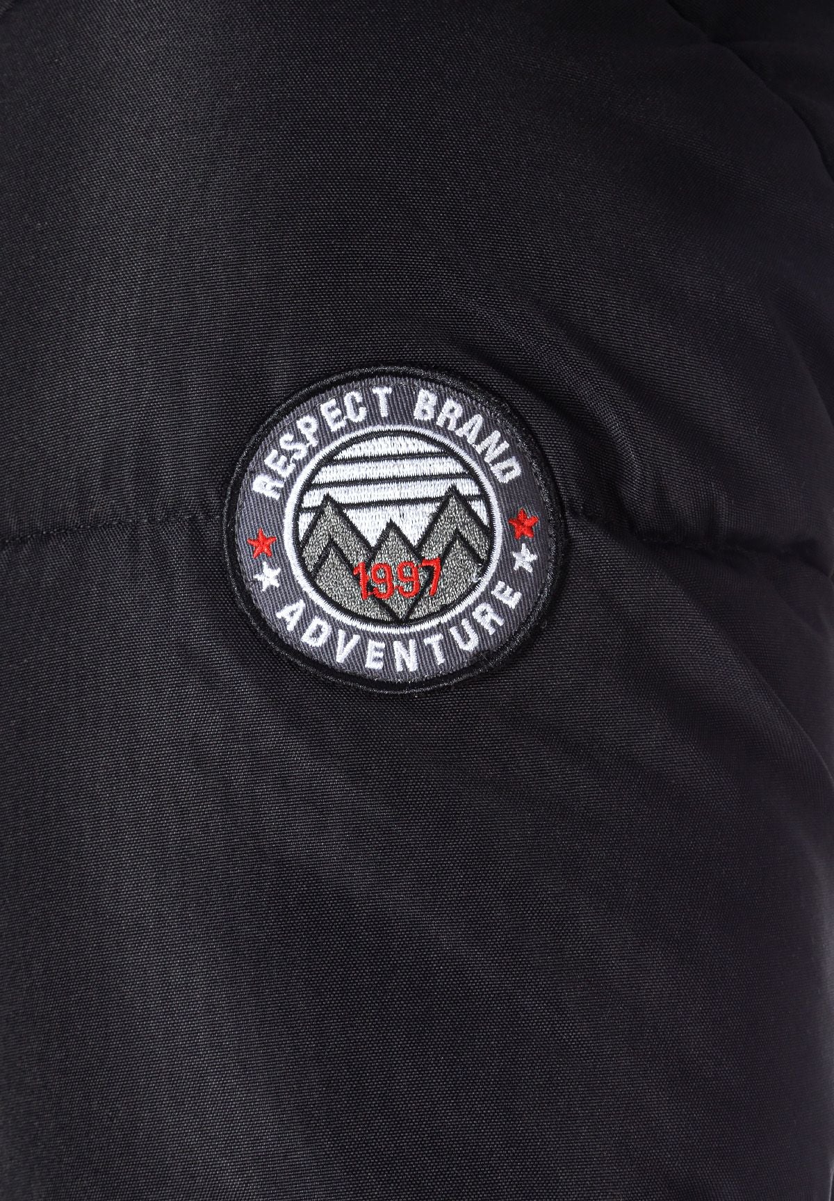 Detail of a black padded jacket sleeve with a logo badge.