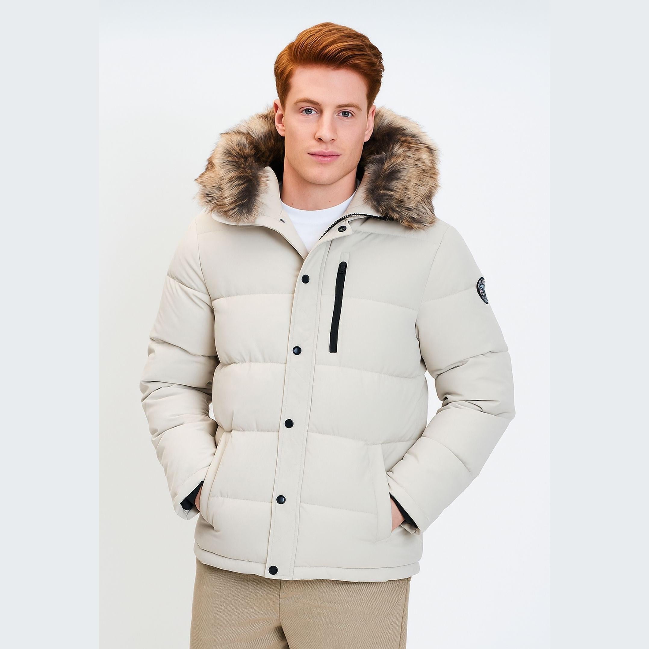 Young man wearing grey padded jacket with faux fur hood trim, front view against white background