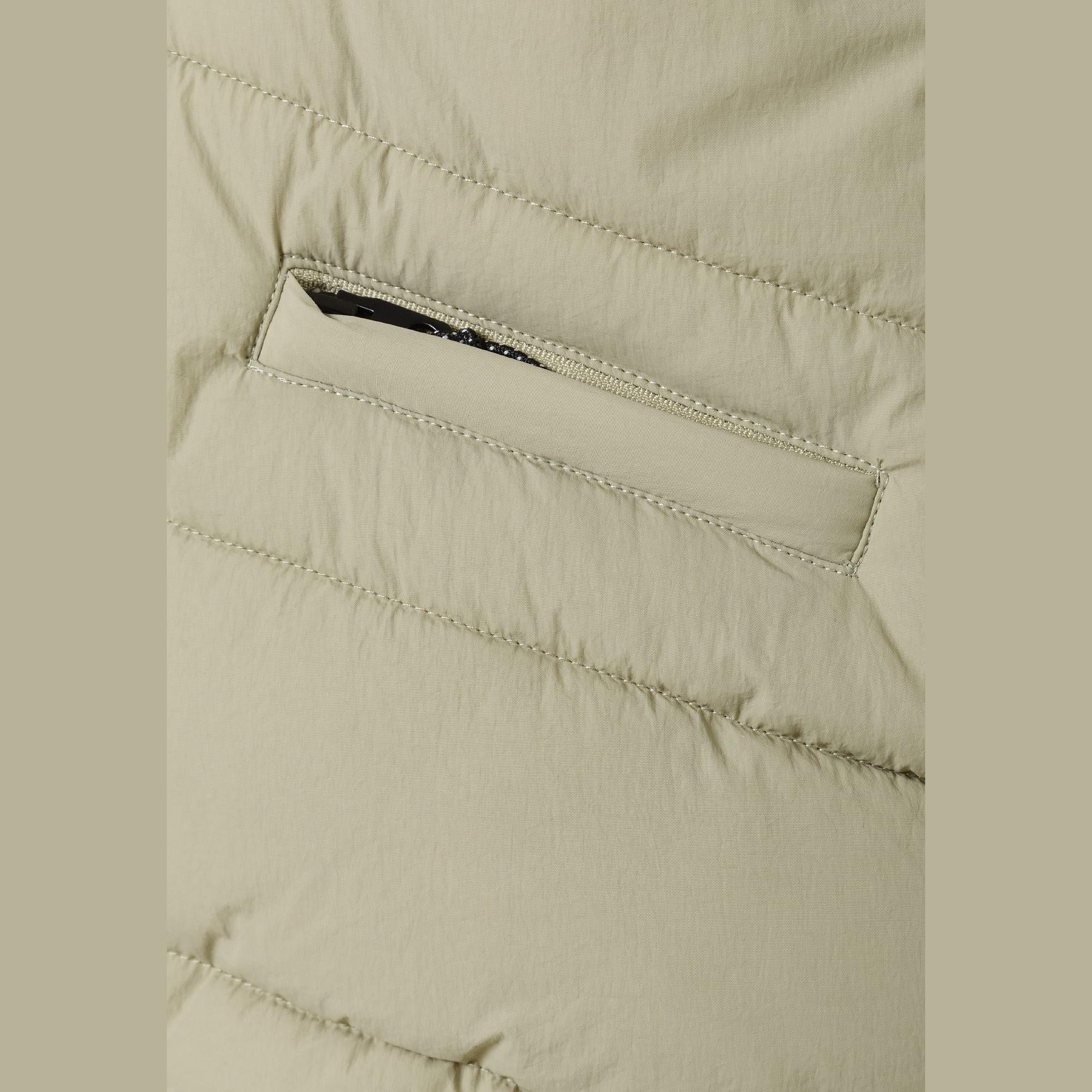 Close-up detail of sage green gilet showing zippered chest pocket and quilted fabric texture