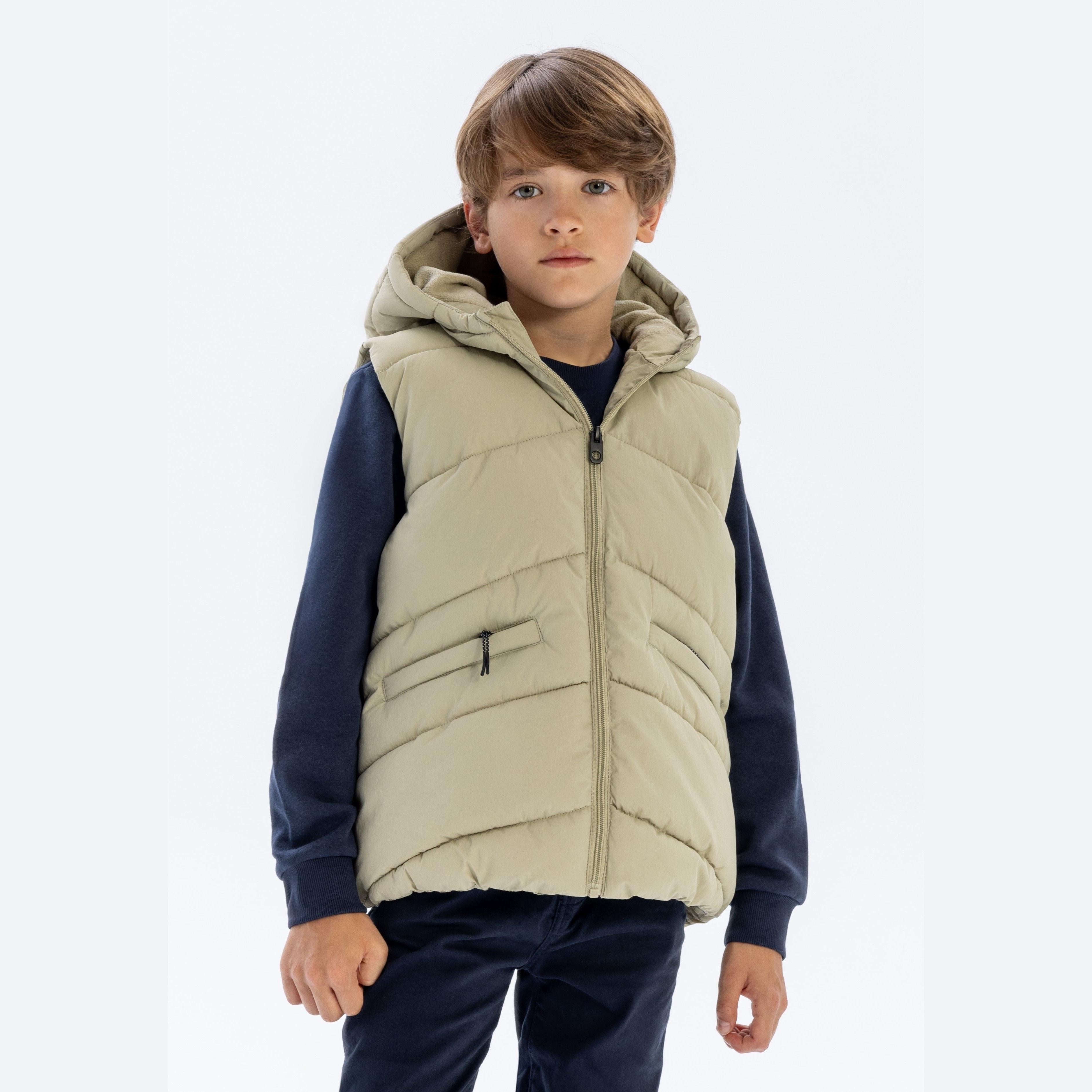Boy wearing sage green padded gilet with hood over navy sweater and jeans, front view against white background