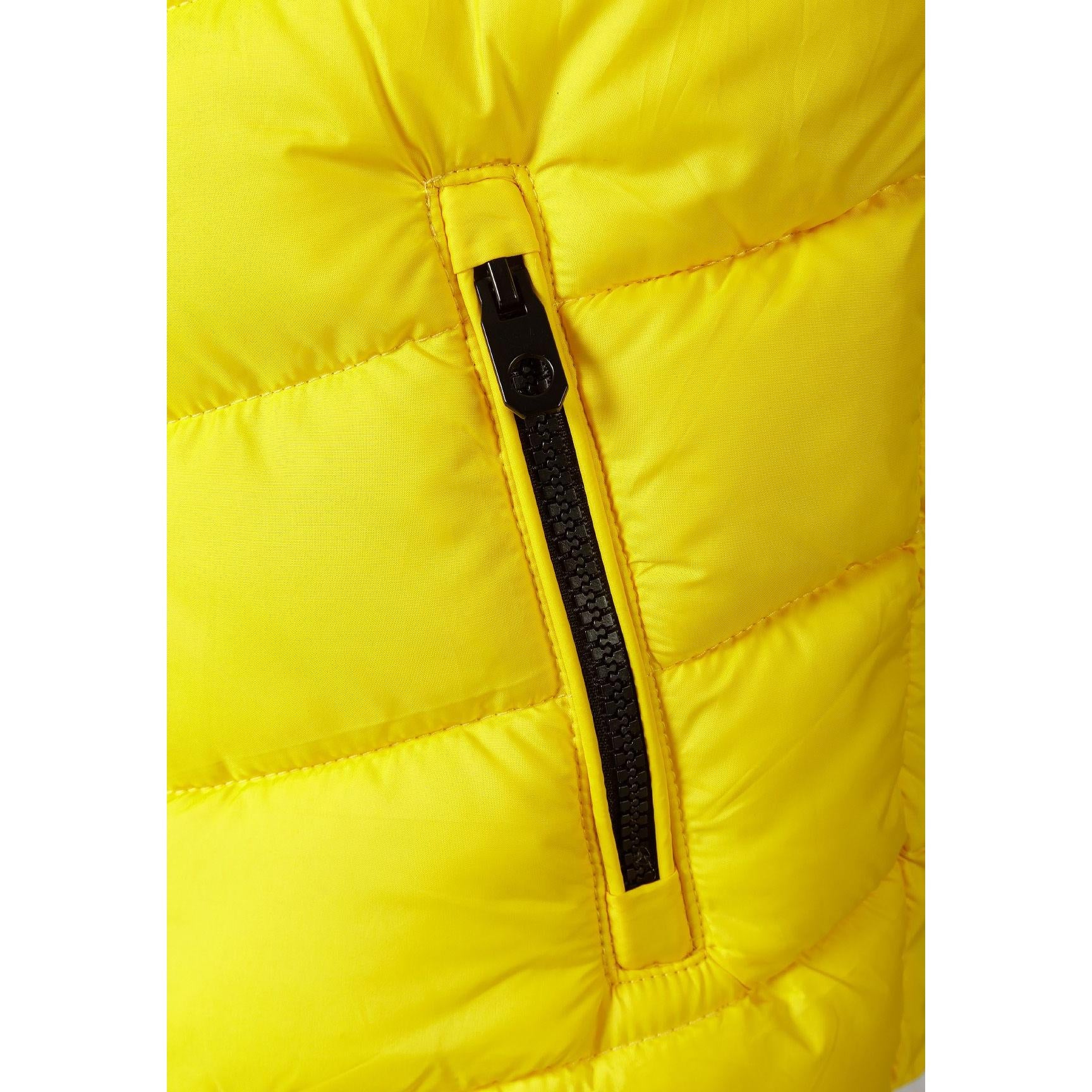 Close-up detail of circular black chest badge with crossed letters design on bright yellow quilted fabric