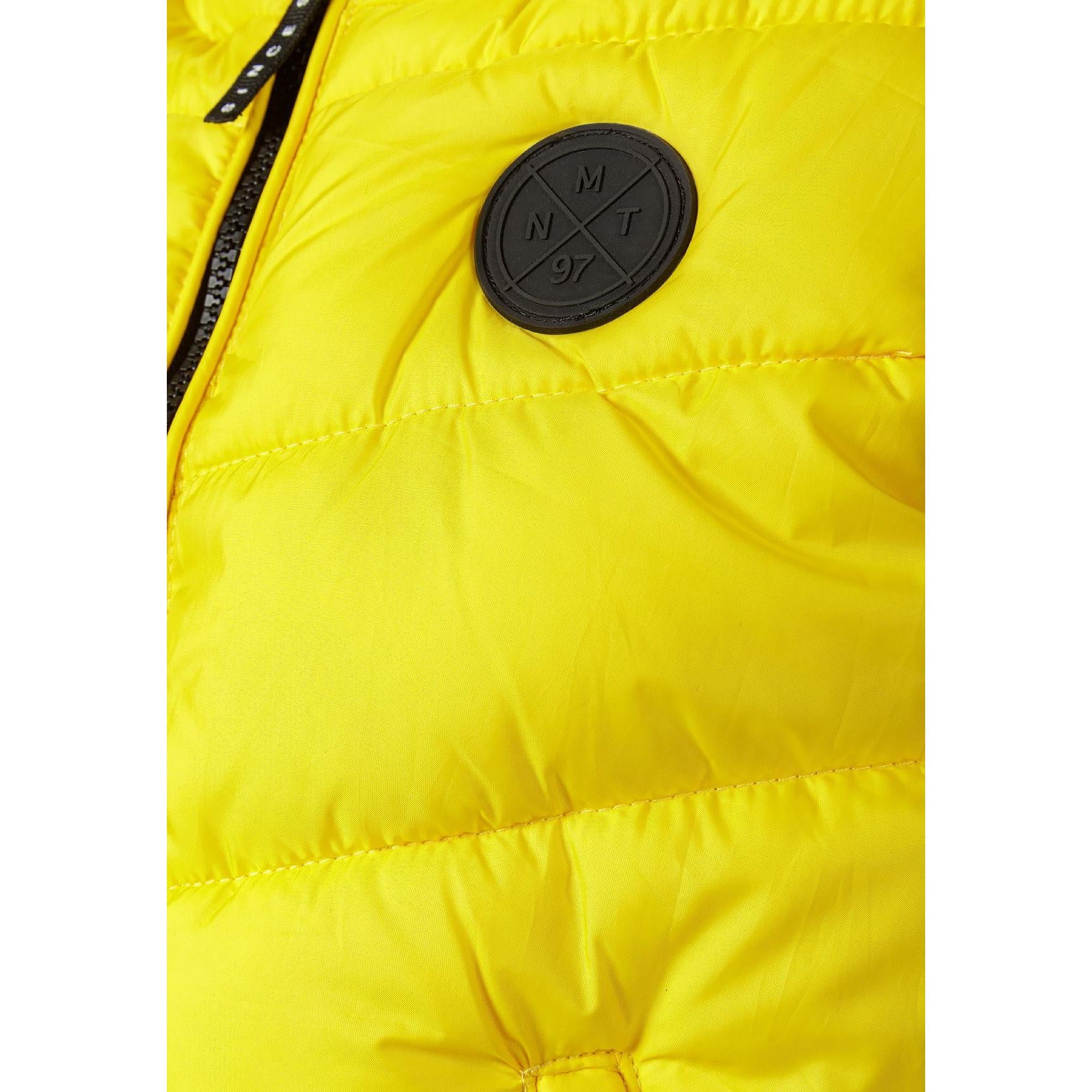 Close-up detail of circular black chest badge with crossed letters design on bright yellow quilted fabric