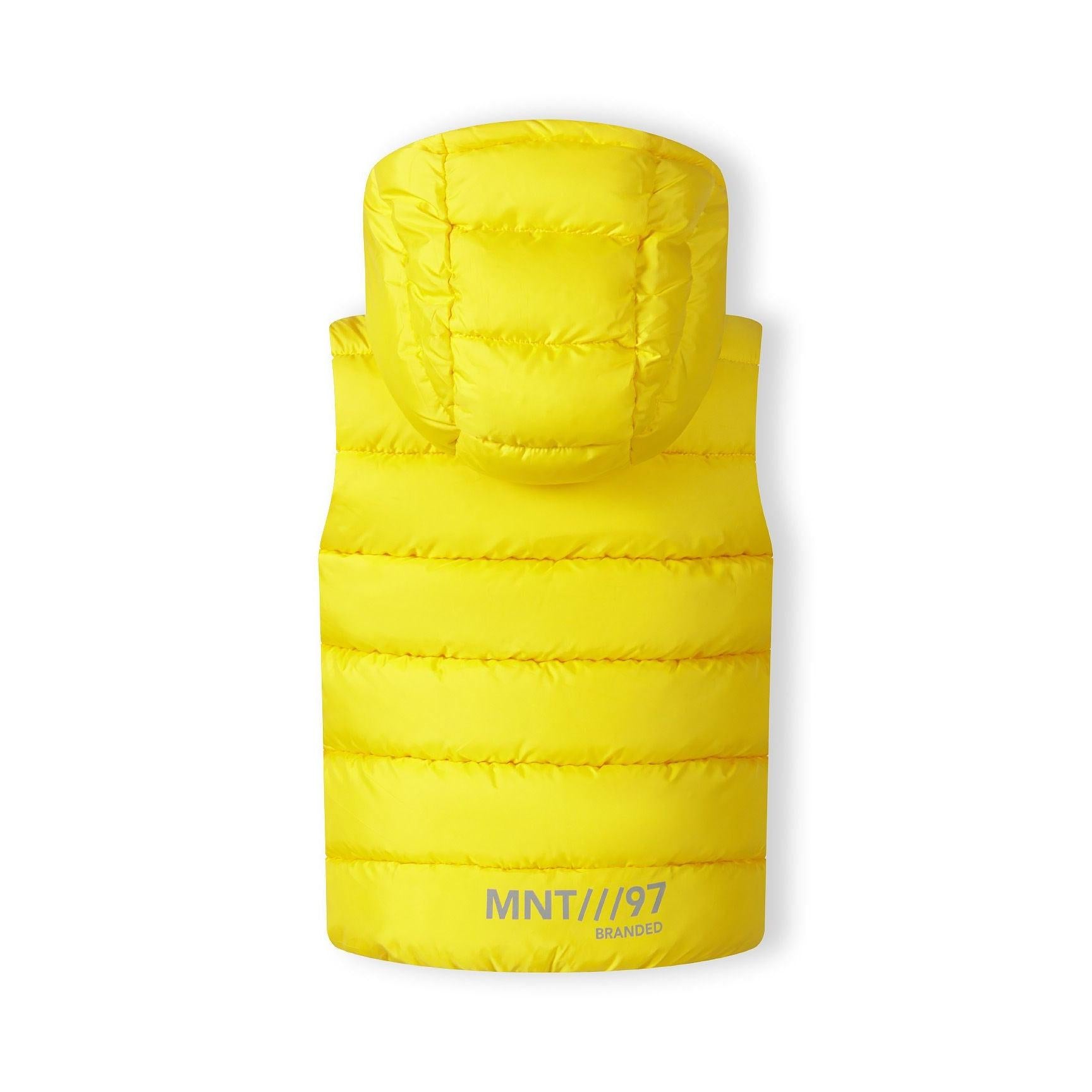 Close-up detail of circular black chest badge with crossed letters design on bright yellow quilted fabric