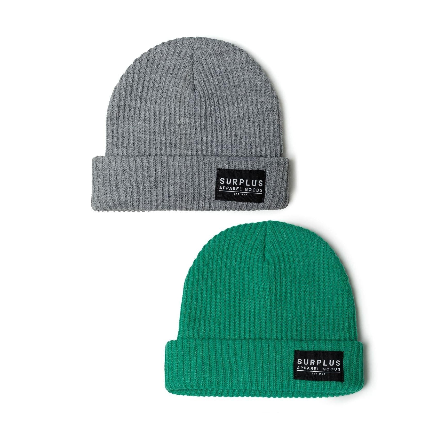 Two ribbed knit beanies displayed on white background, one grey and one green, both featuring black Surplus Apparel Goods labels