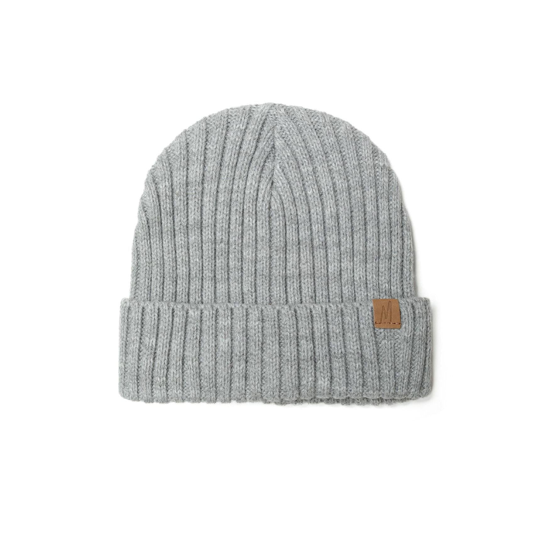 Close-up of grey ribbed knit beanie showing detailed ribbed texture, folded cuff and brown leather-look tab on white background