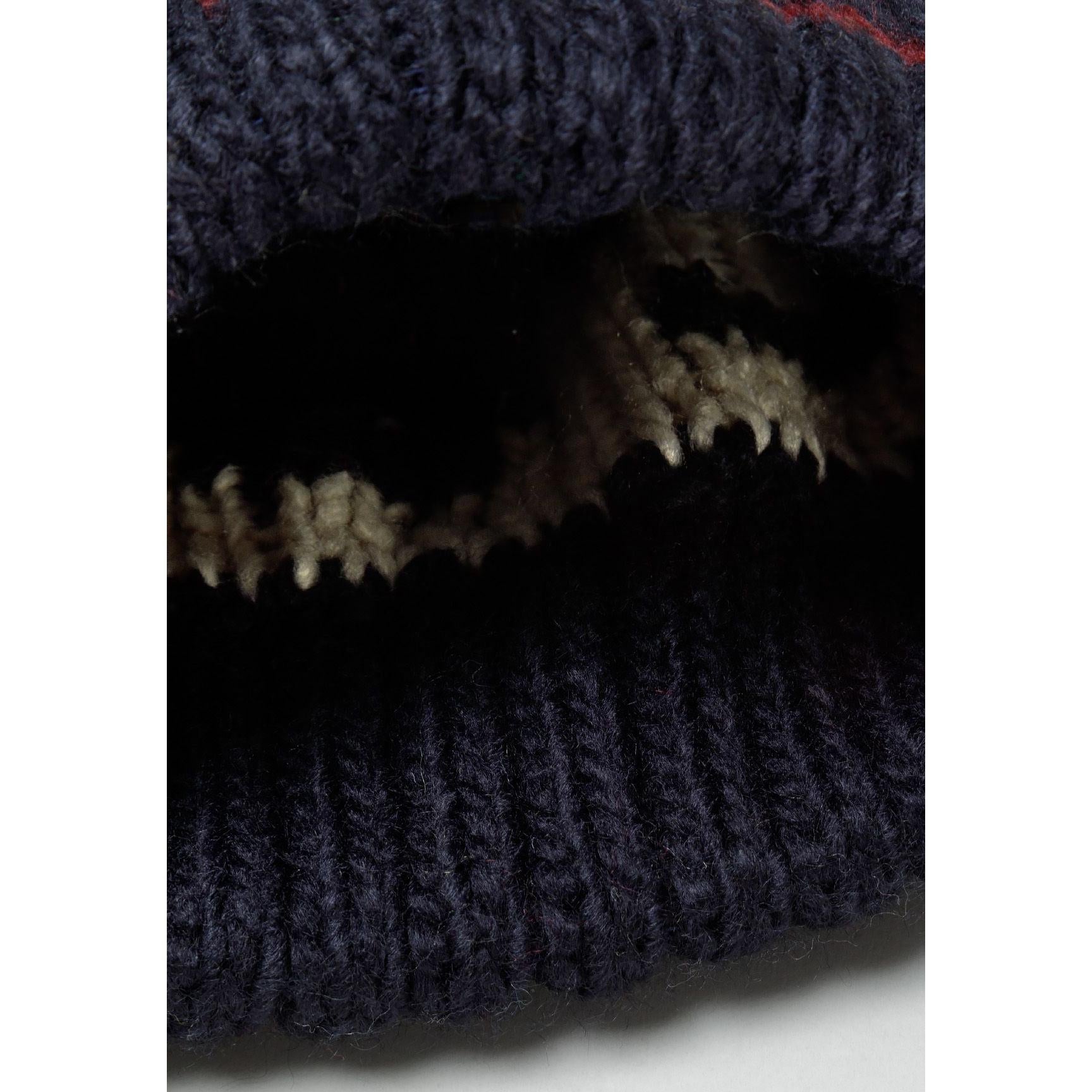 Detail view of navy knitted beanie interior showing ribbed construction and white jacquard pattern from inside perspective