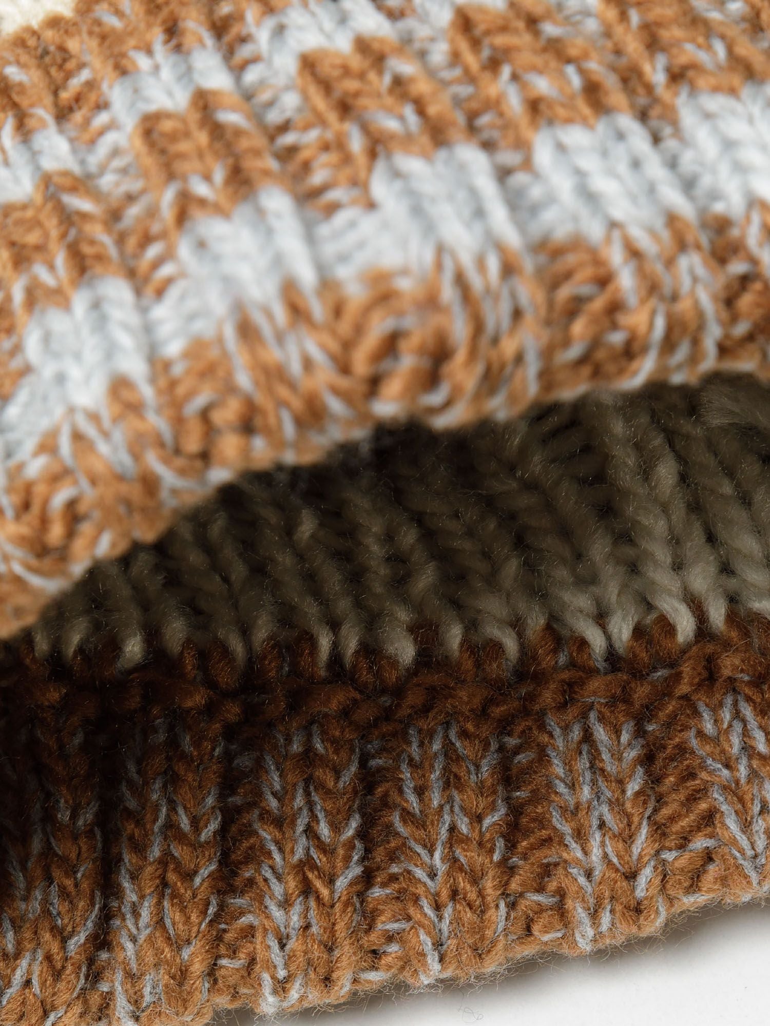 Detail of a boys jacquard hat in beige with textured knit patterns.