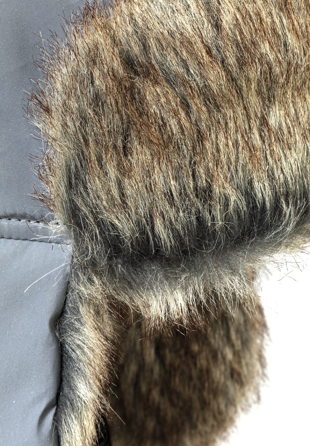 Detail of a grey unisex trapper hat with faux fur lining and adjustable ear flaps.