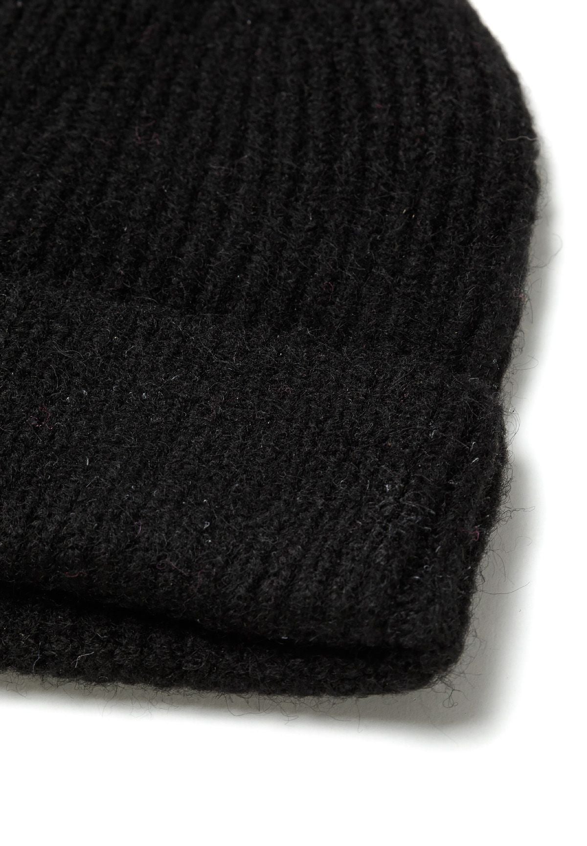 Close-up of a black knitted beanie hat with a structured hem.
