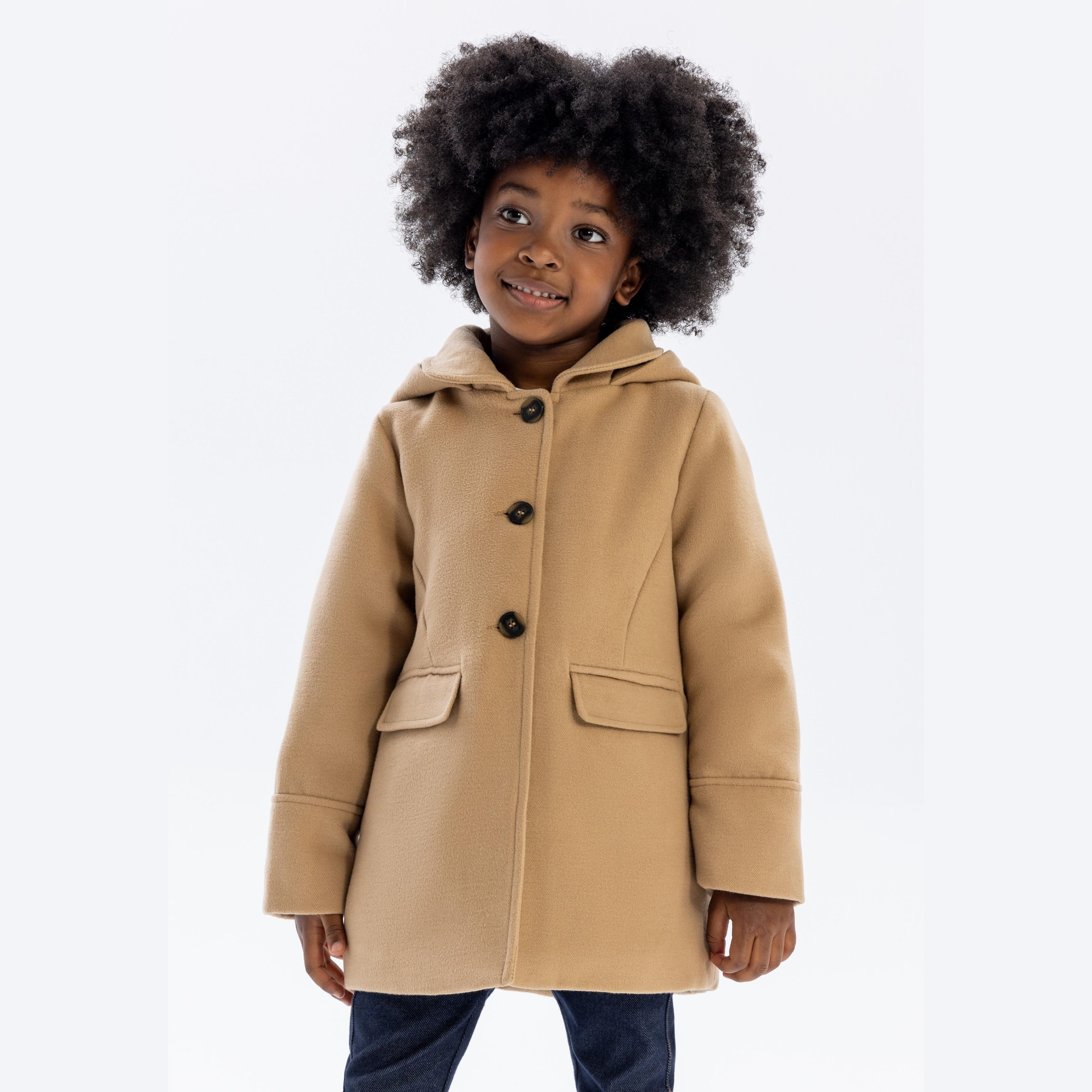 Young girl wearing beige padded coat with hood, button fastening and front pockets, paired with jeans on white background