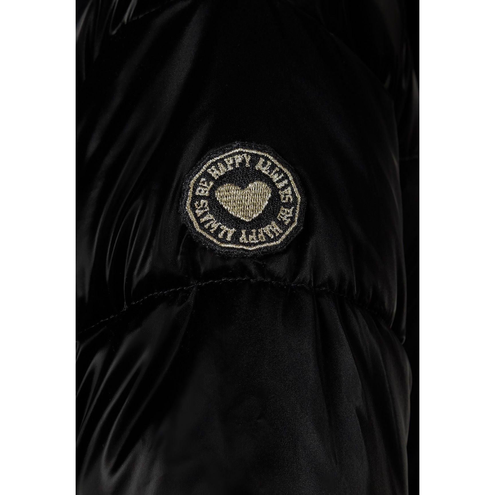 Close-up detail of circular embroidered patch on black jacket sleeve featuring heart design with text around border