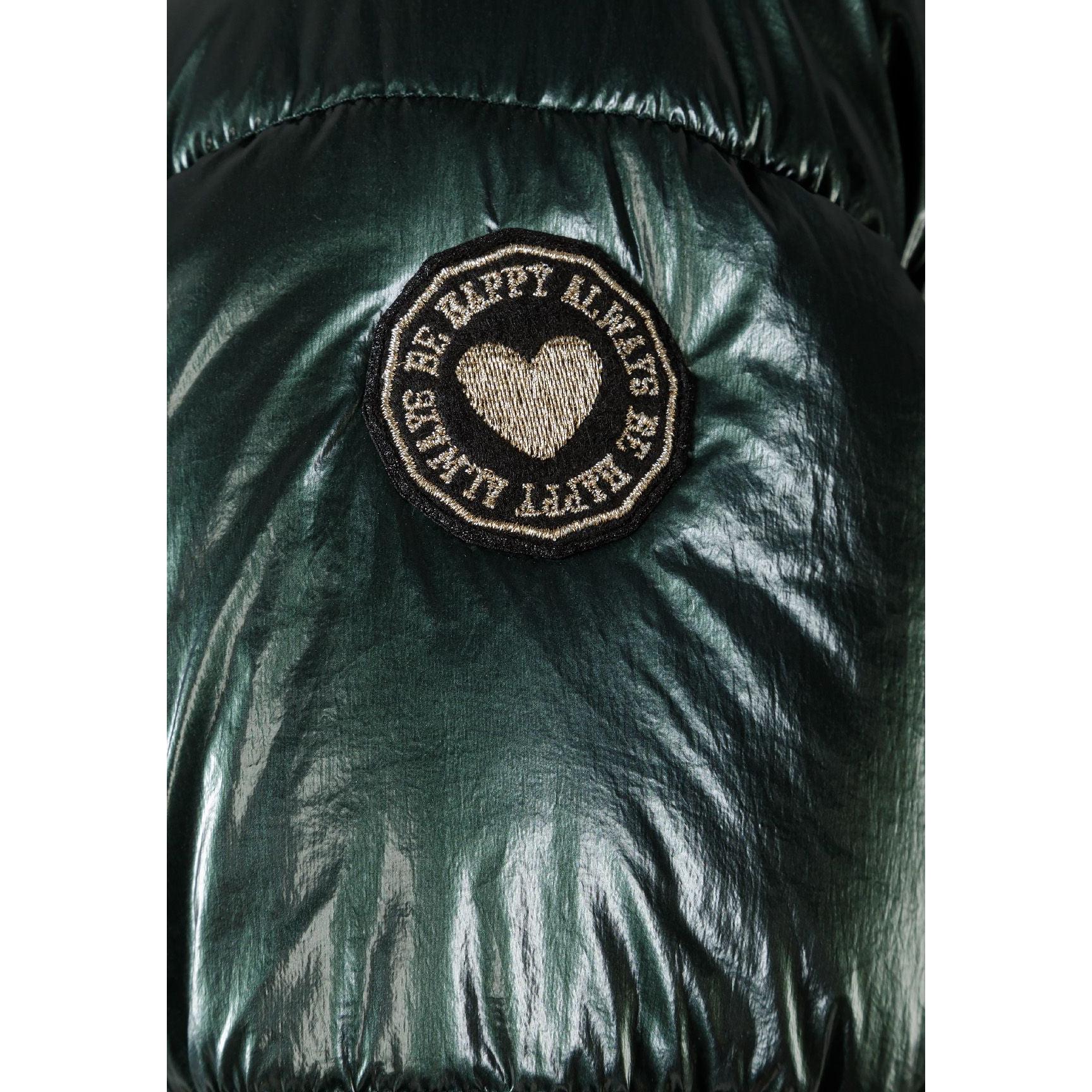 Close-up detail of embroidered circular patch with heart design and text on green metallic jacket fabric