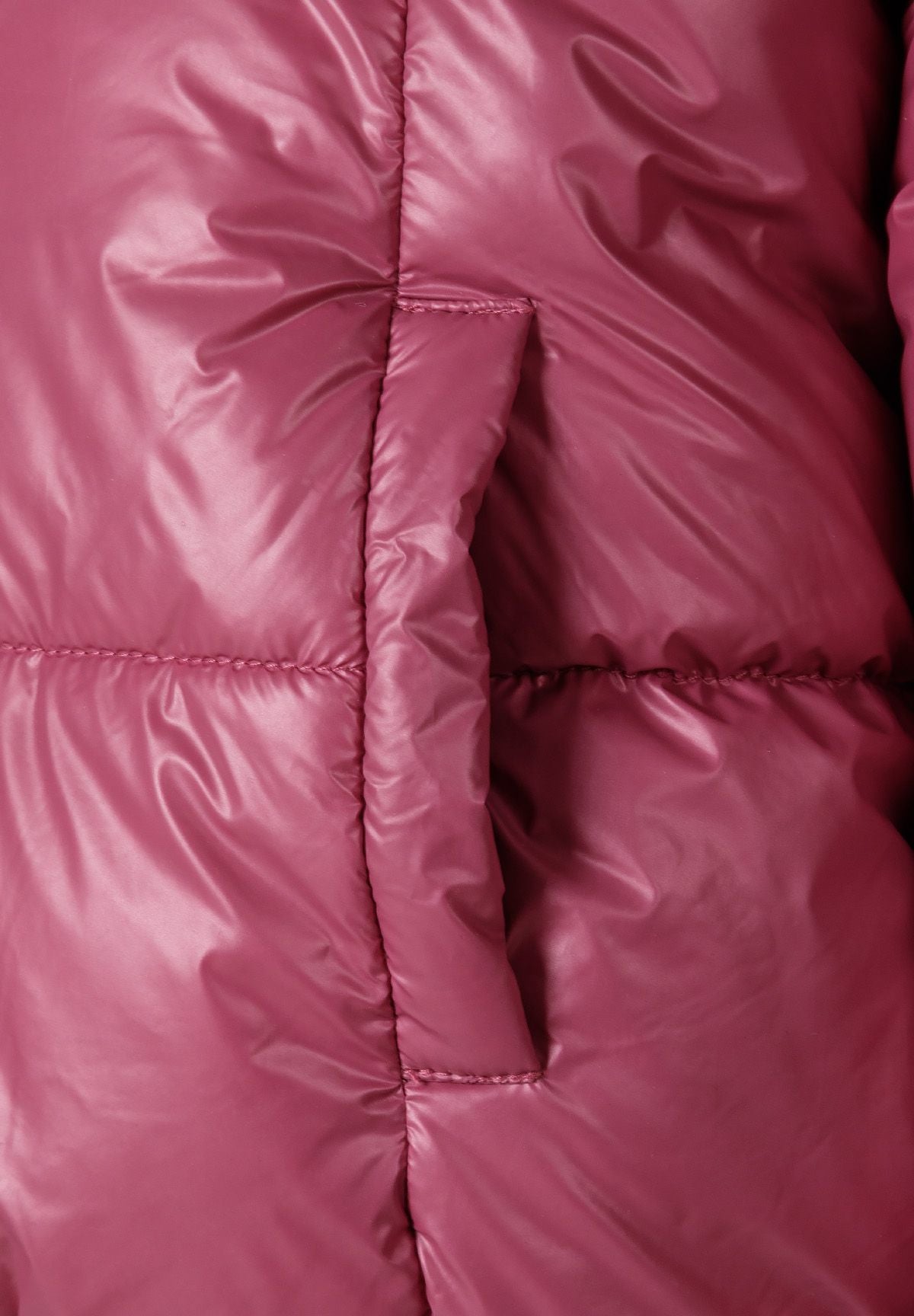 Detail of a padded reversible jacket in metallic purple with a front zip and ribbed cuffs.