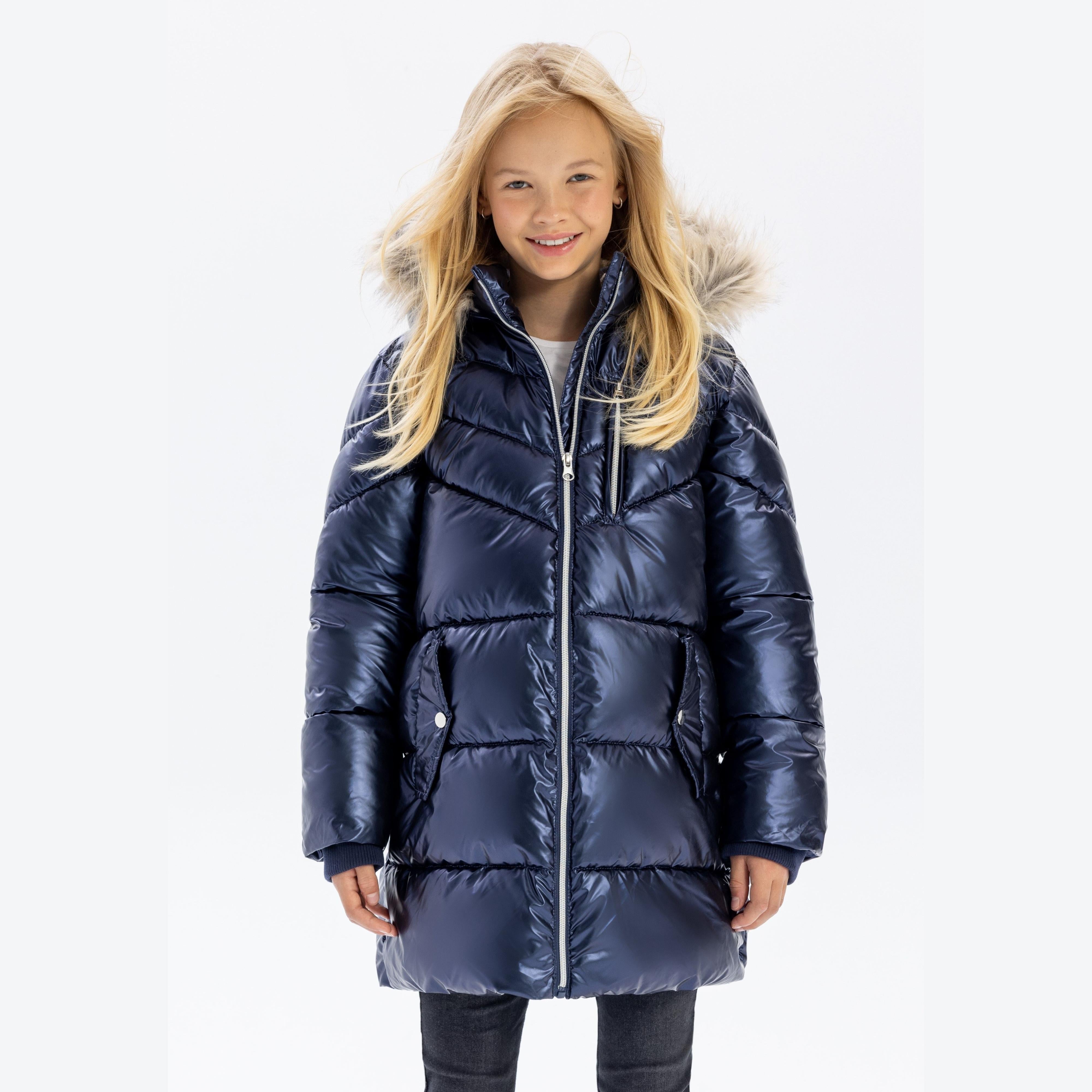 Young girl wearing navy quilted winter parka with detachable faux fur hood trim, full length view on white background