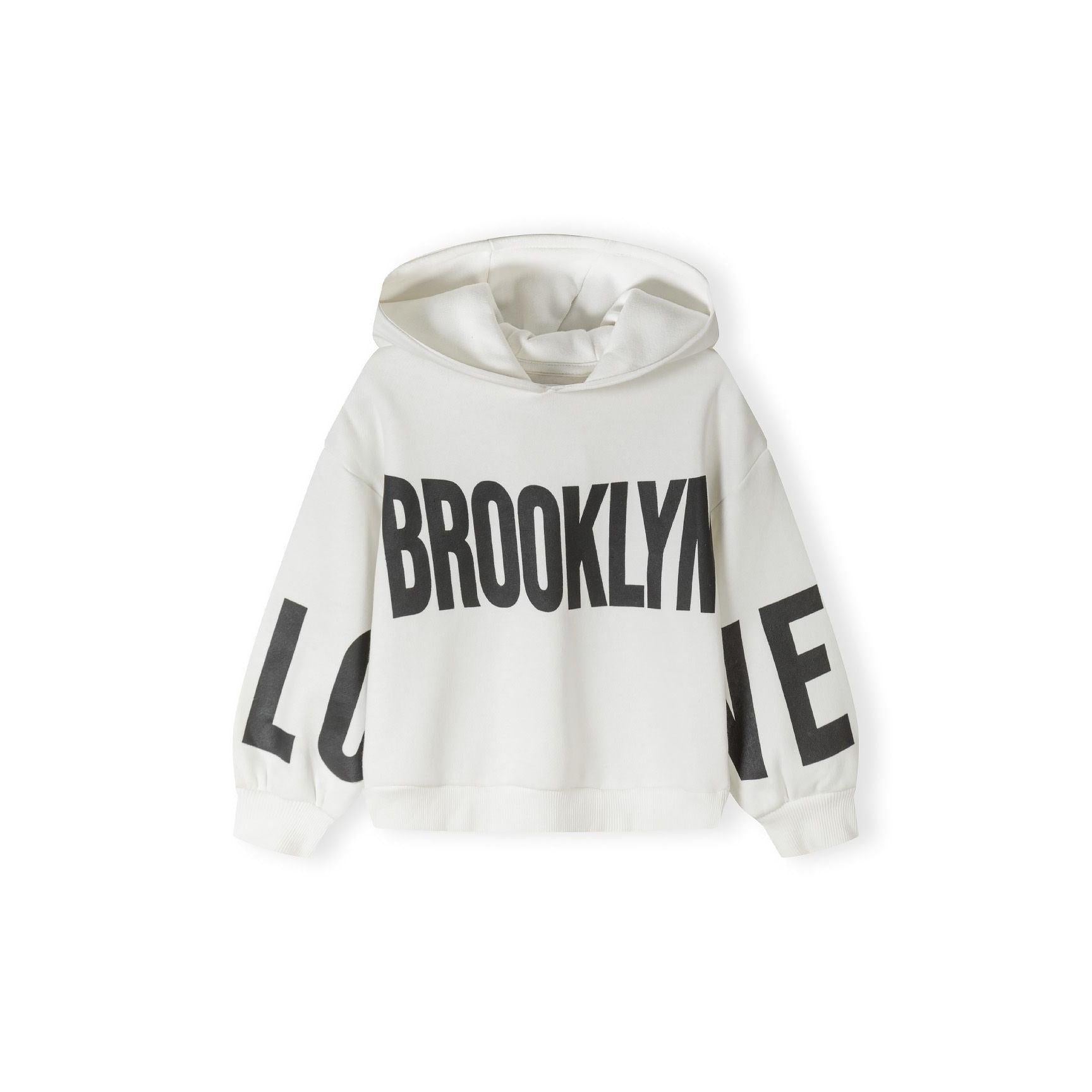 Close-up detail of white joggers showing black printed text on leg and elasticated waistband construction