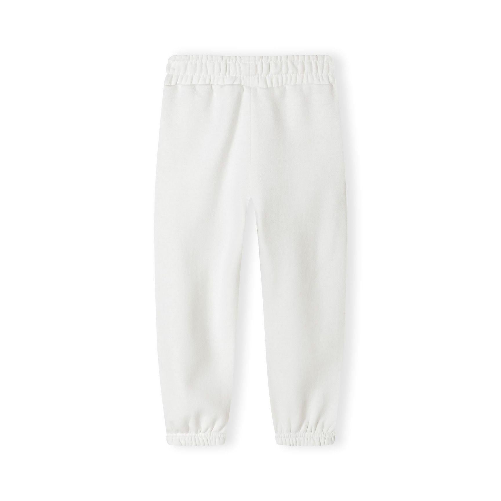 Close-up detail of white joggers showing black printed text on leg and elasticated waistband construction