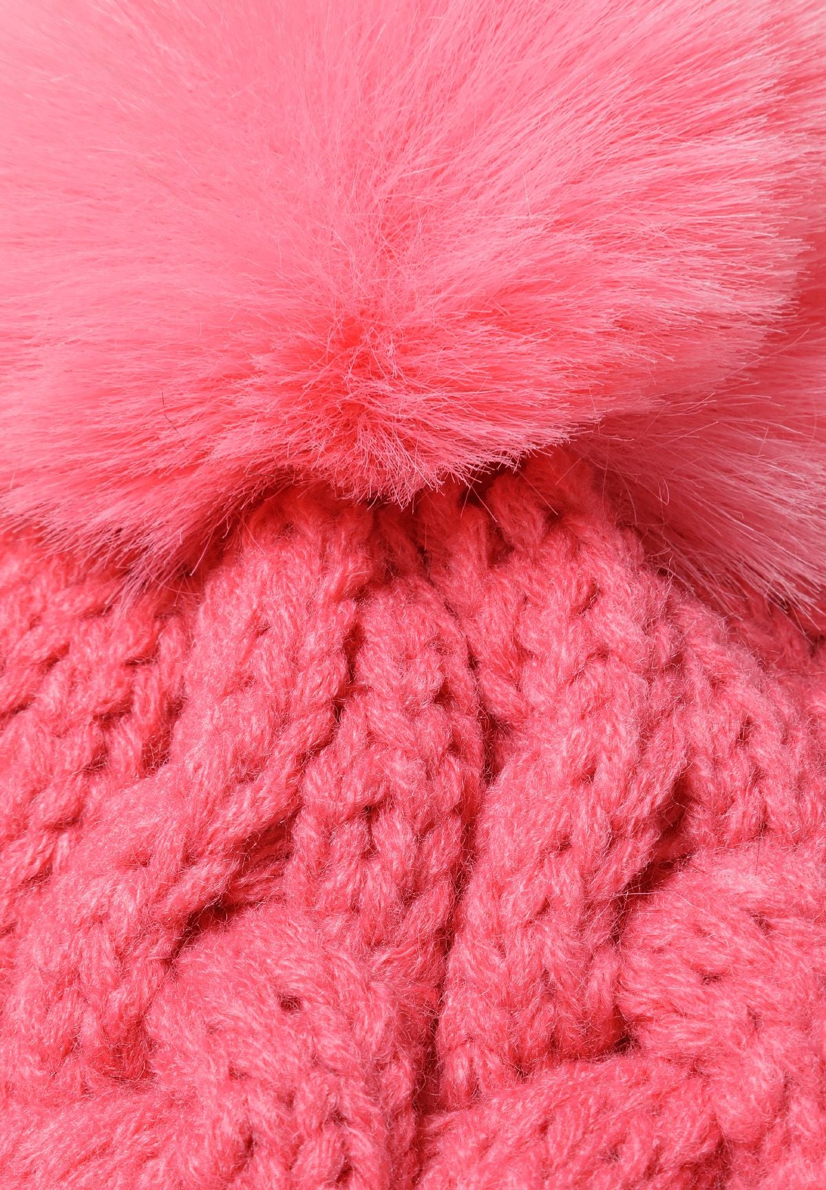 Bright pink cable-knit bobble hat, pompom and cable detail.
