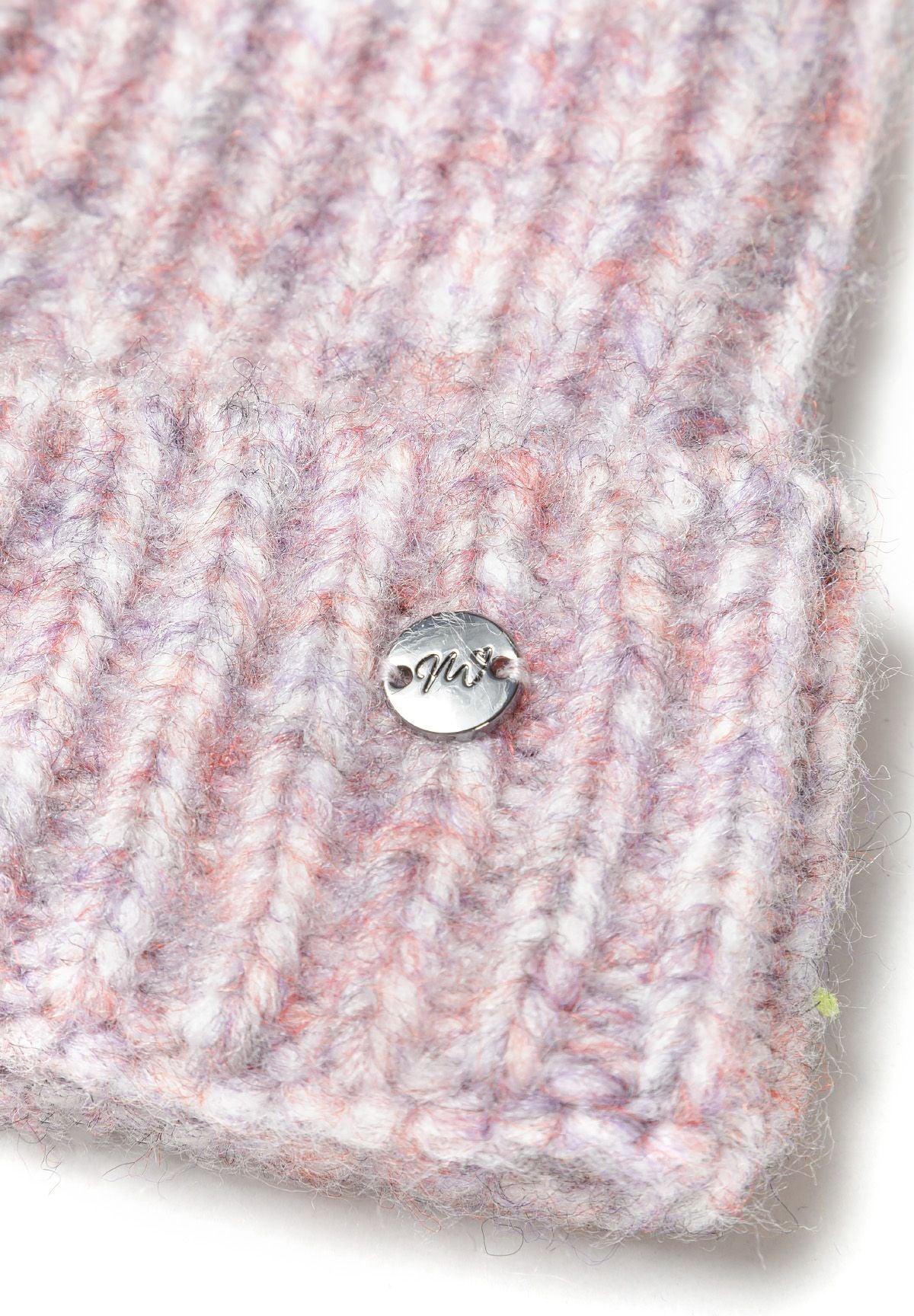 Detail of a girls' knitted yarn hat in light pink with multicolour accents and a small metal badge.