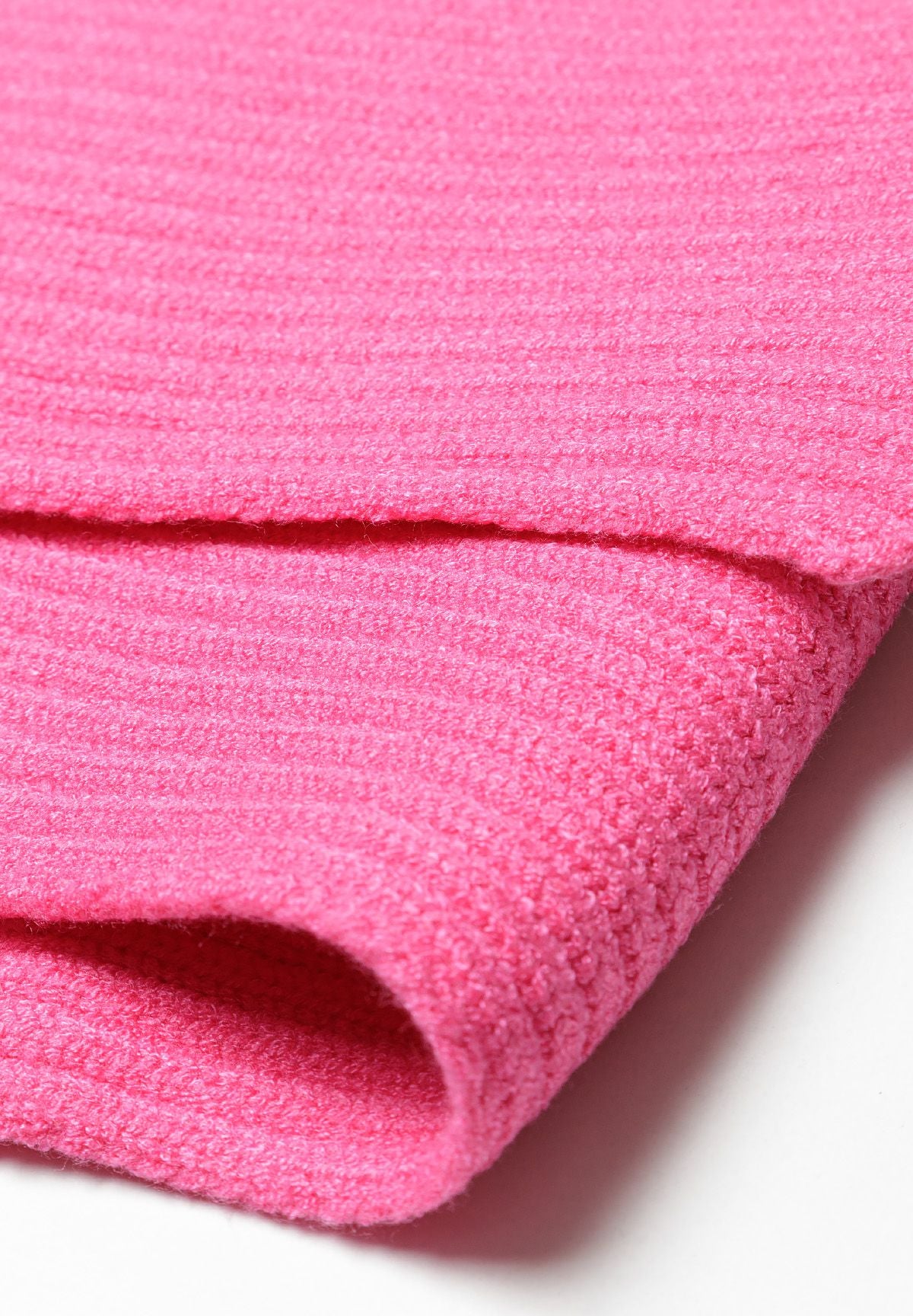 Detail of a pink knitted hat and scarf set with rib pattern.