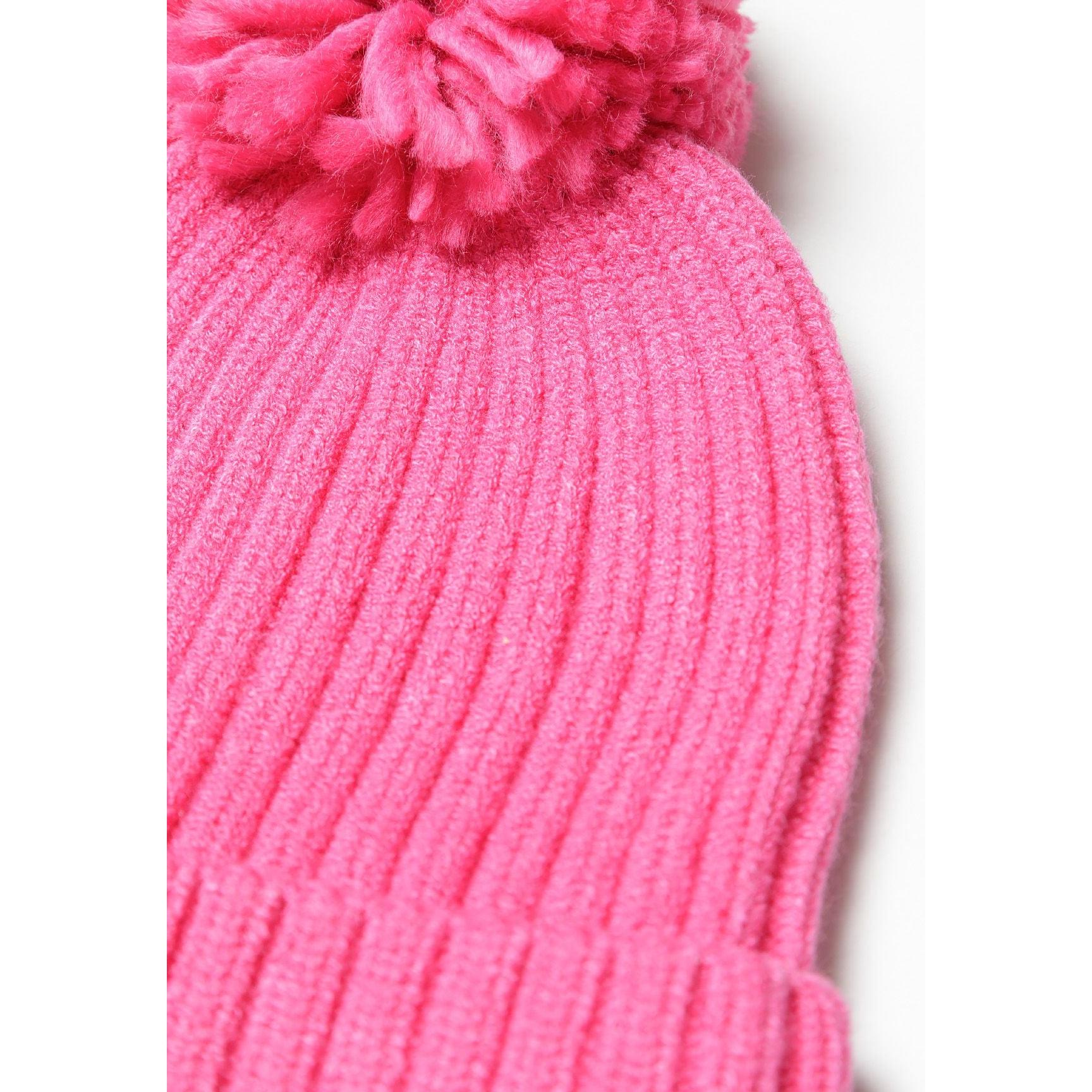 Close-up detail of pink ribbed knit beanie hat showing texture and fluffy pom pom against white background