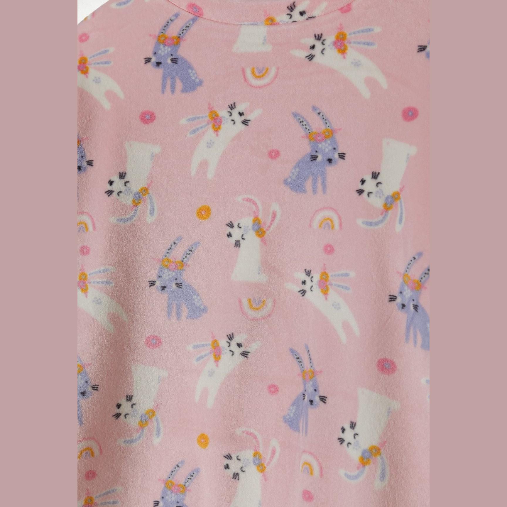 Close-up detail of pink velour fabric showing unicorn characters with rainbow and dot pattern