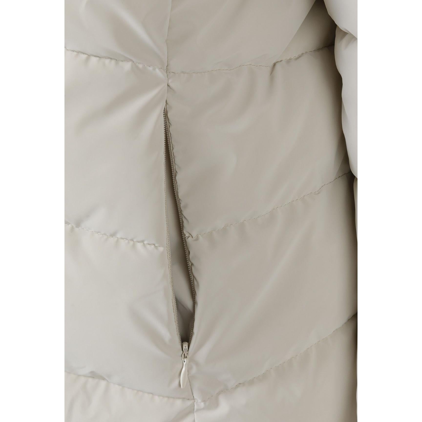 Close-up detail of cream jacket showing quilted stitching pattern and zip fastening