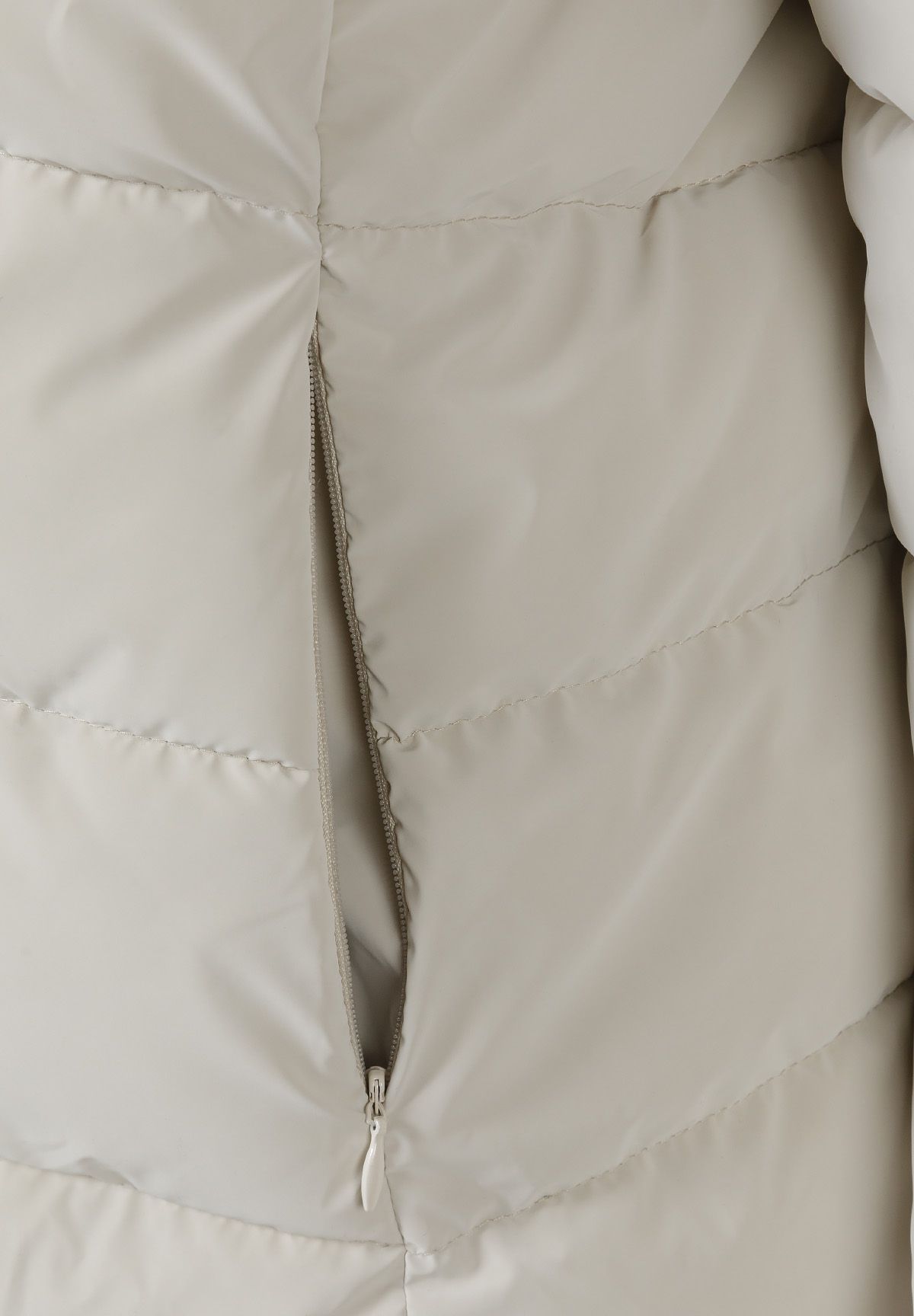 Detail of a padded jacket with a zip closure and quilted design.