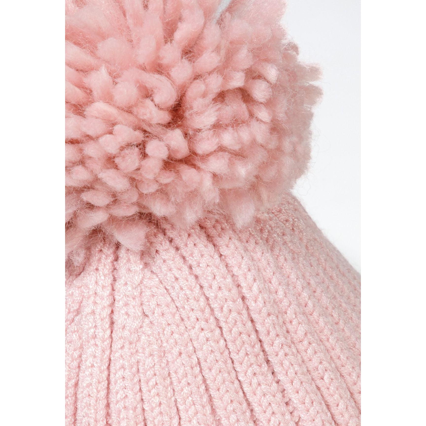 Close-up detail of pink pom pom texture showing fluffy yarn construction on white background