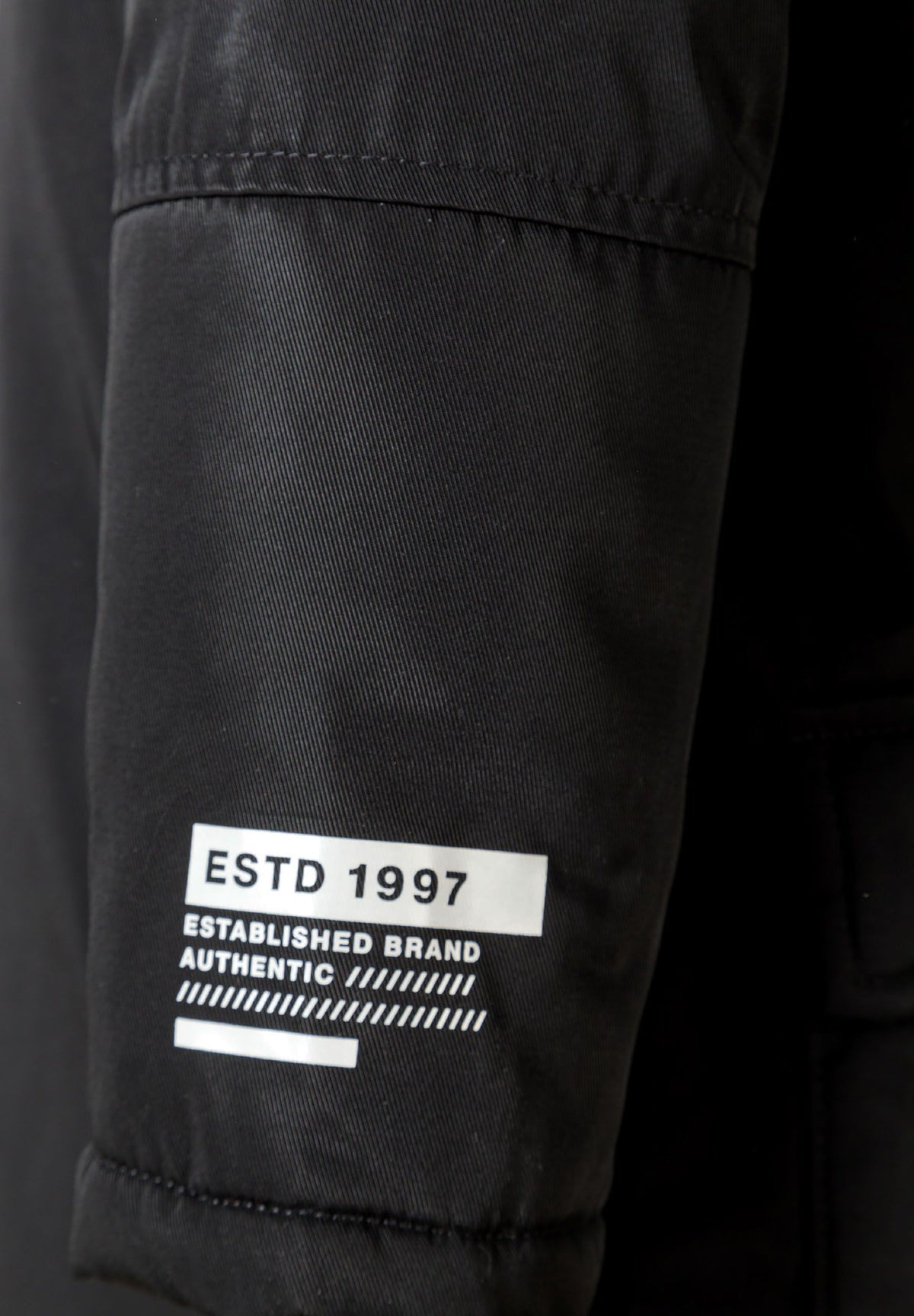 Close-up of the sleeve lettering on the black parka.