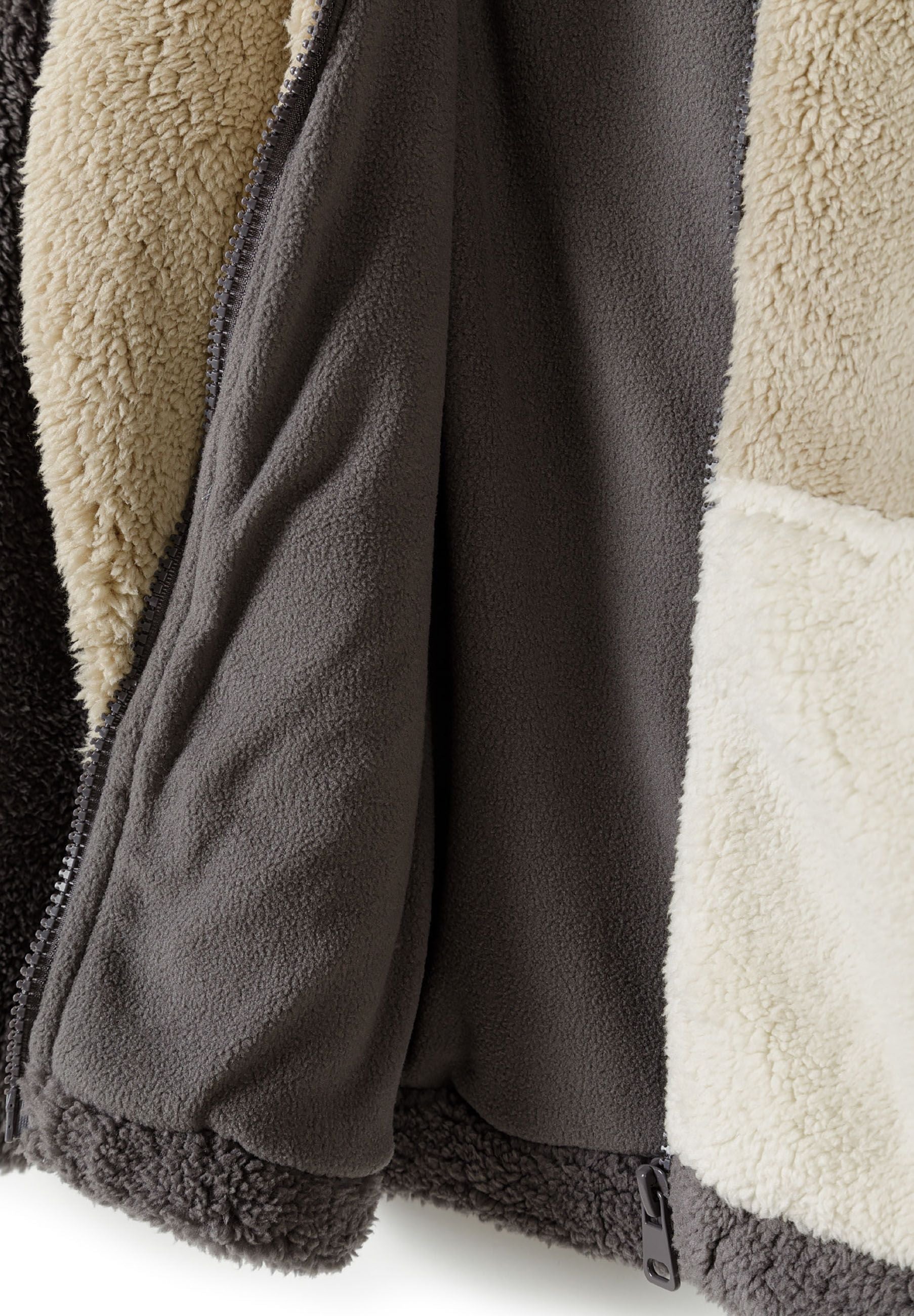 Detail of boys sherpa fleece jacket showing soft fleece lining and contrasting cream pocket.