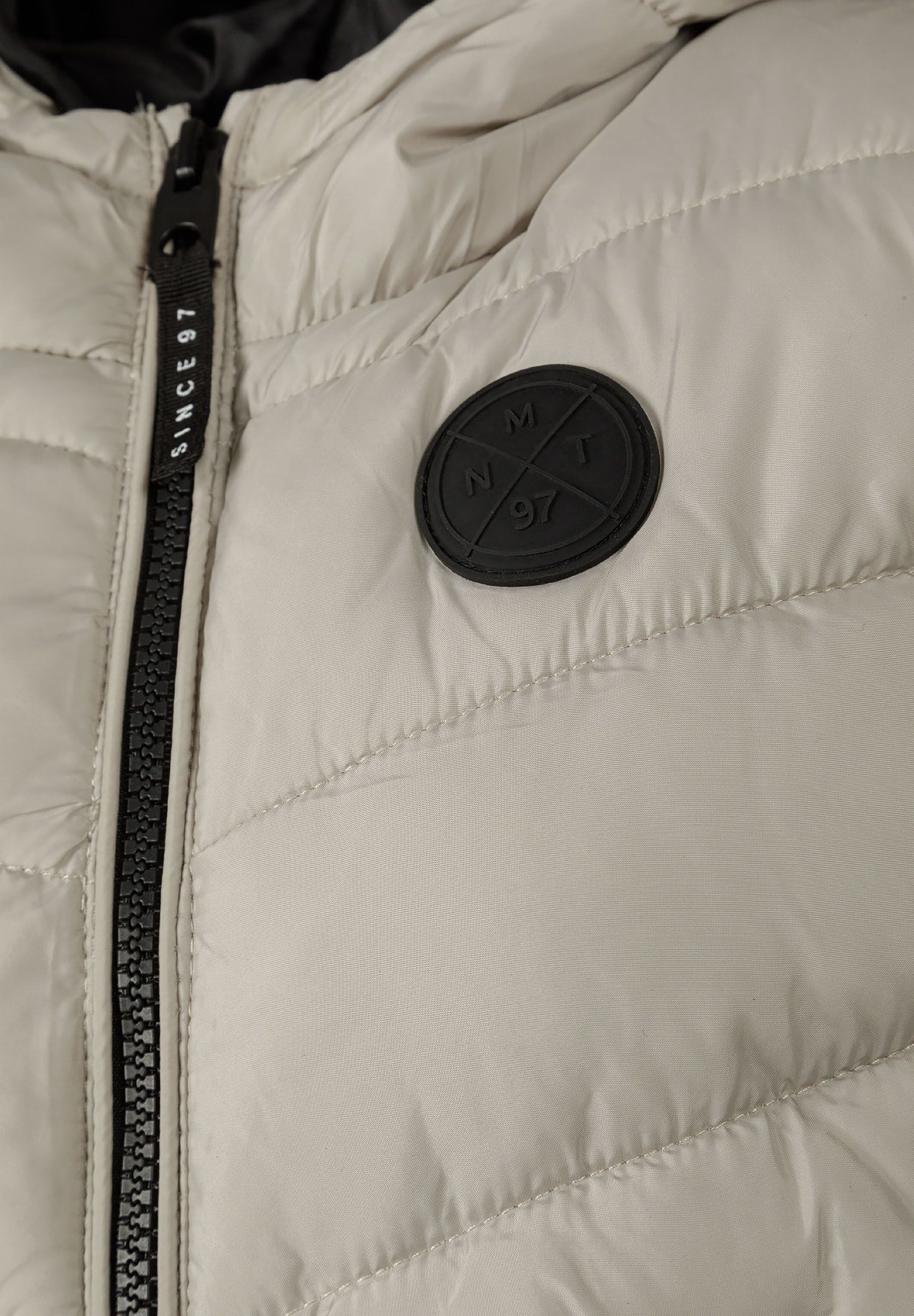Detail of boys gilet with fixed hood, full-length zip, and chest badge.