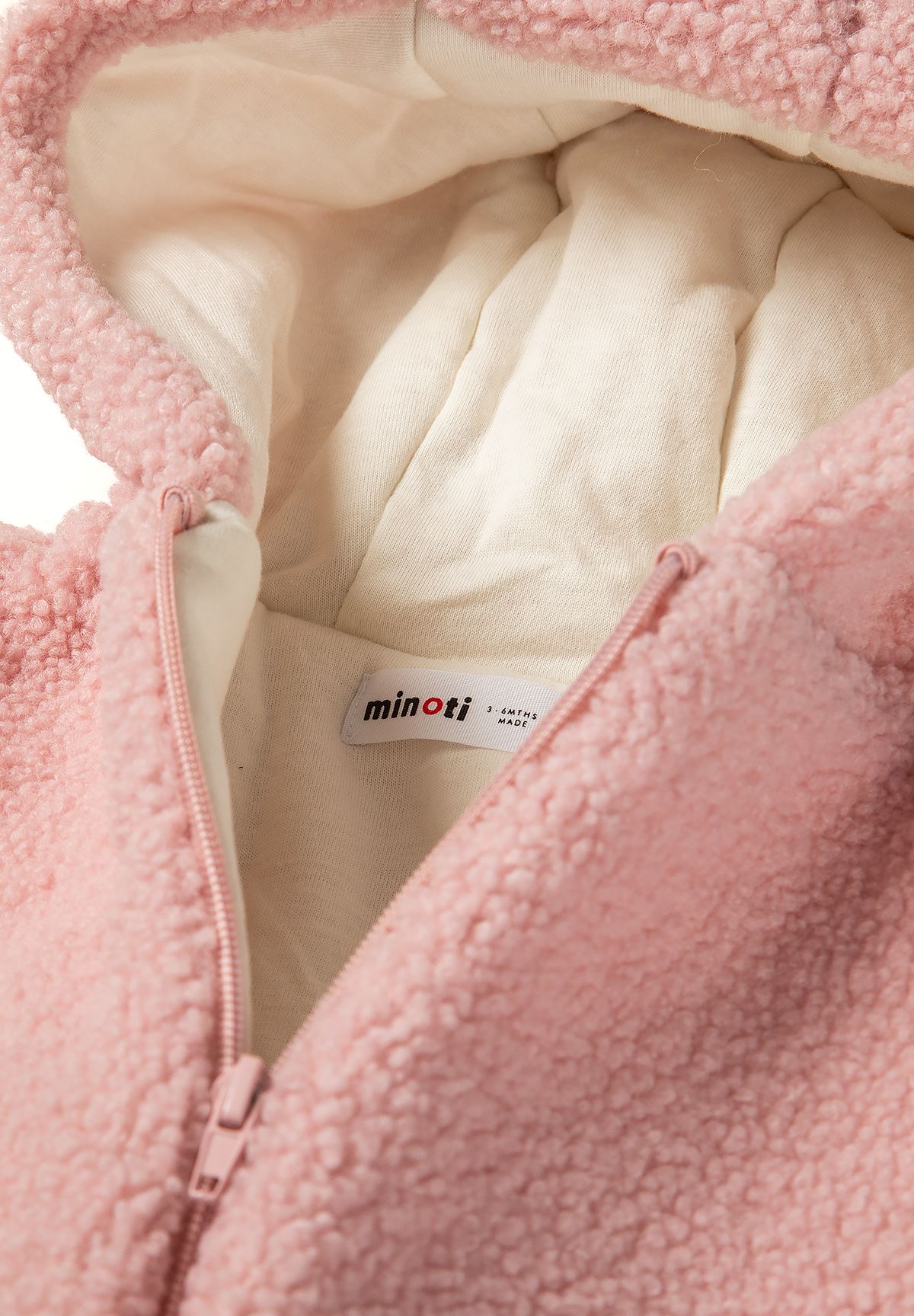 Detail of light pink sherpa snowsuit with front zip and soft lining.
