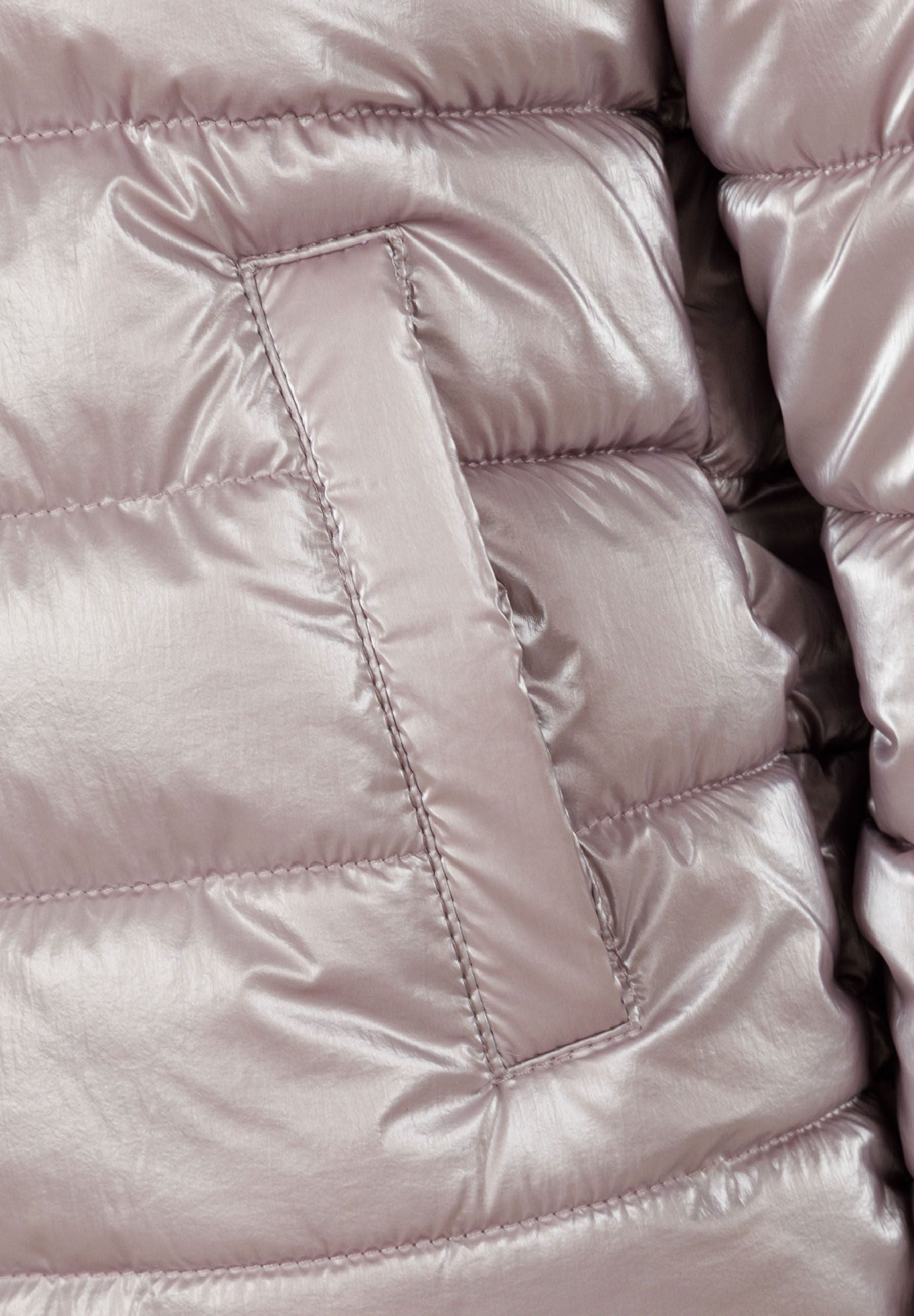 Detail of a lilac padded winter jacket with quilted texture and pocket.