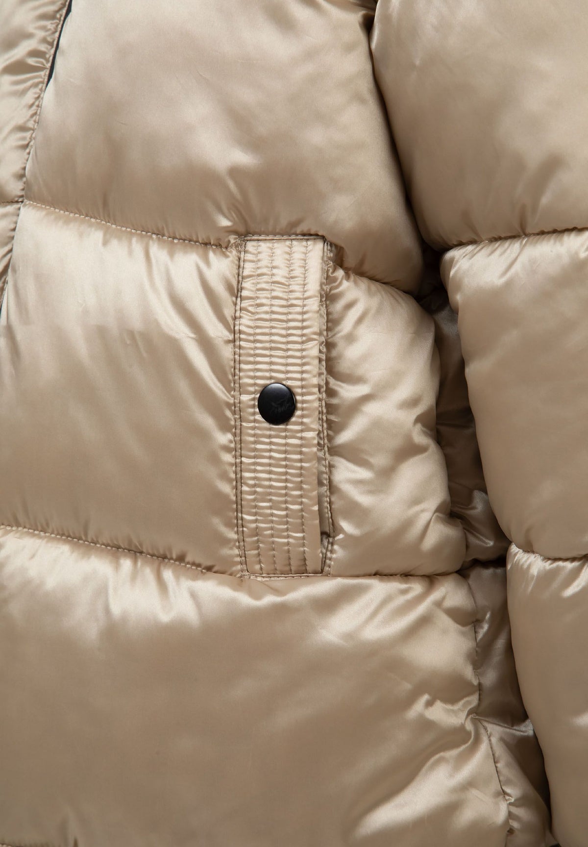 Close-up of a textured gold pocket tab and black snap on the shiny quilted parka.