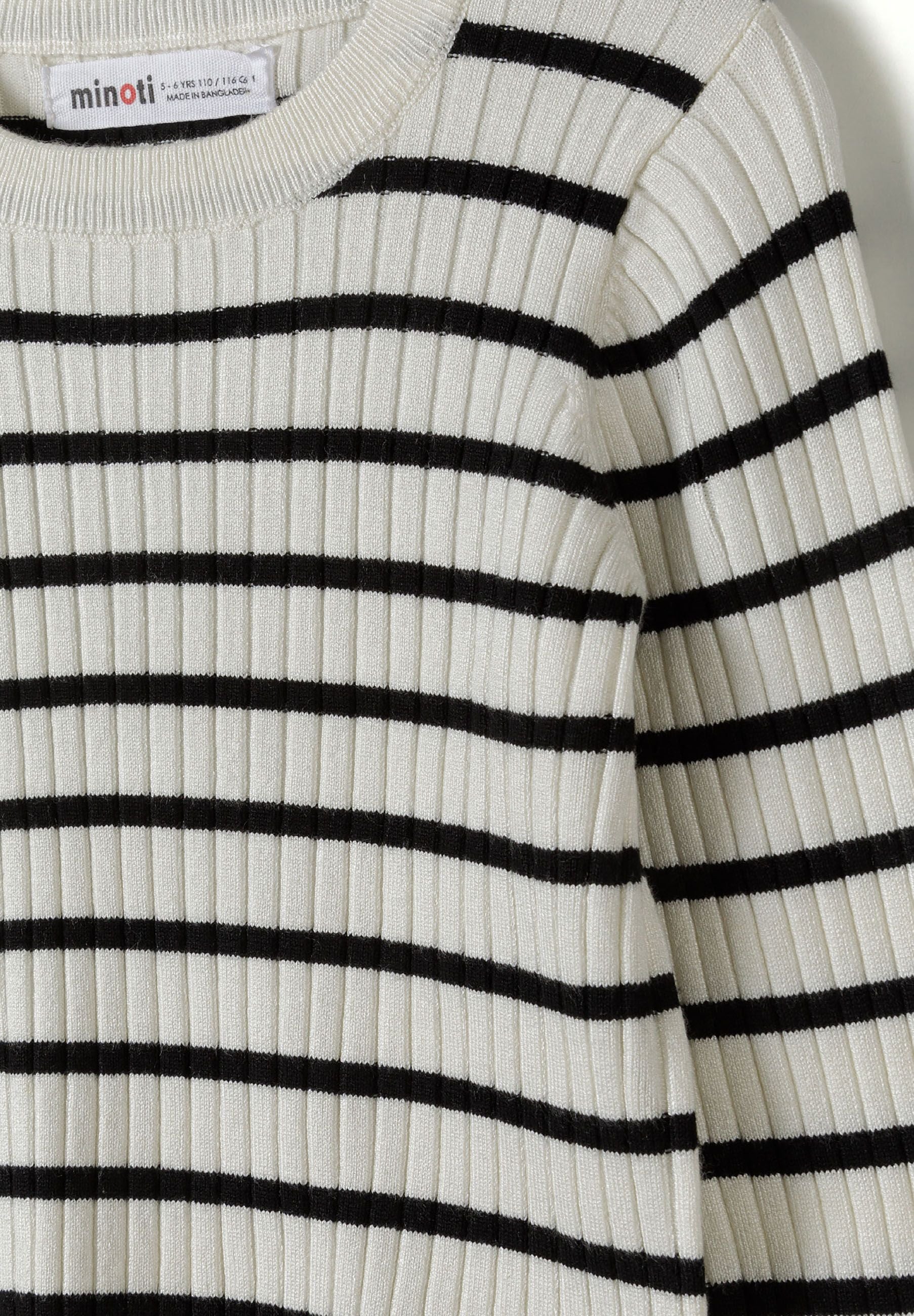 Detail of a girls ribbed jumper in cream with black stripes, featuring a round neckline and long sleeves.