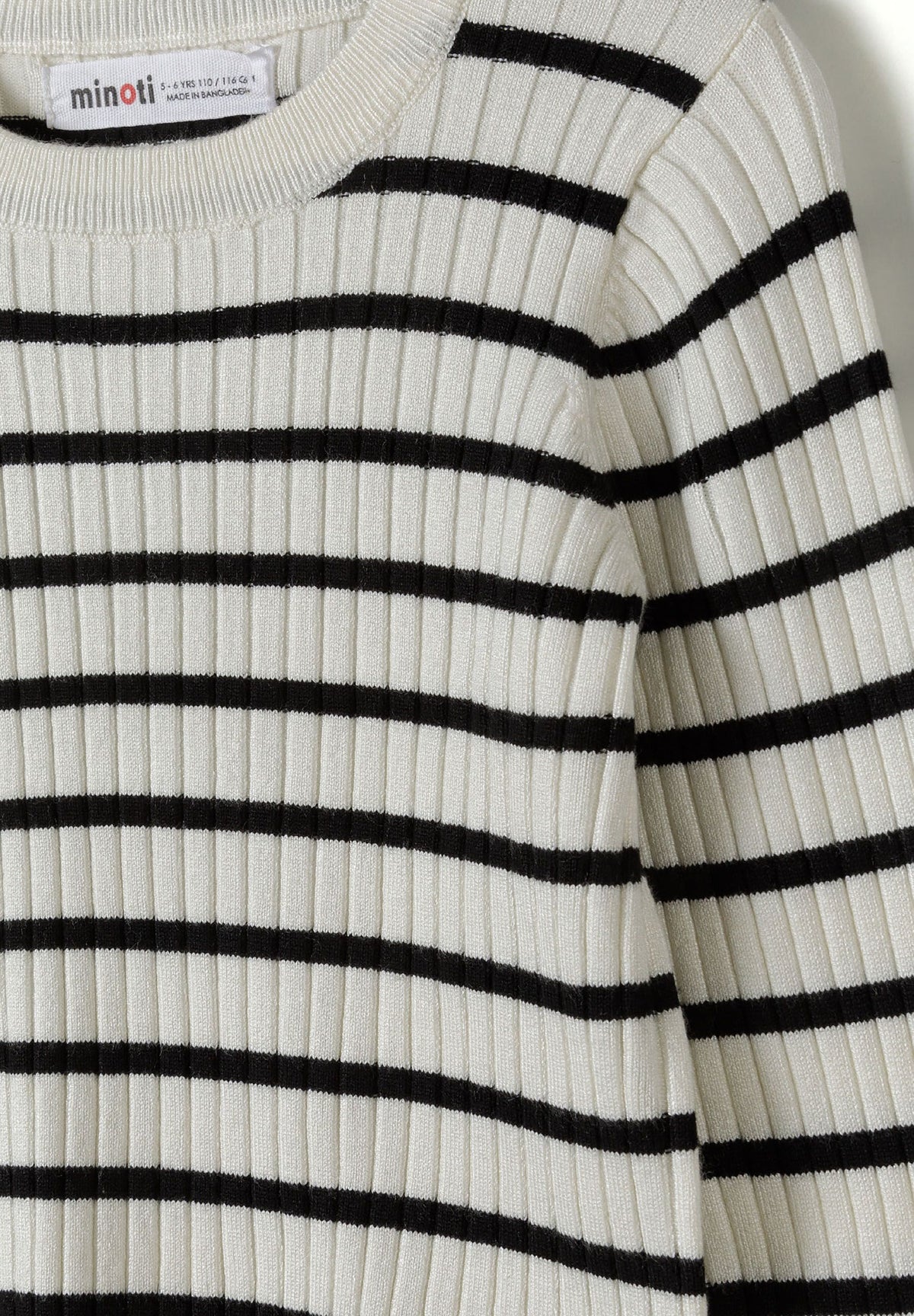Close-up of cream vertical rib knit crossed by narrow black stripes at the crew neck.