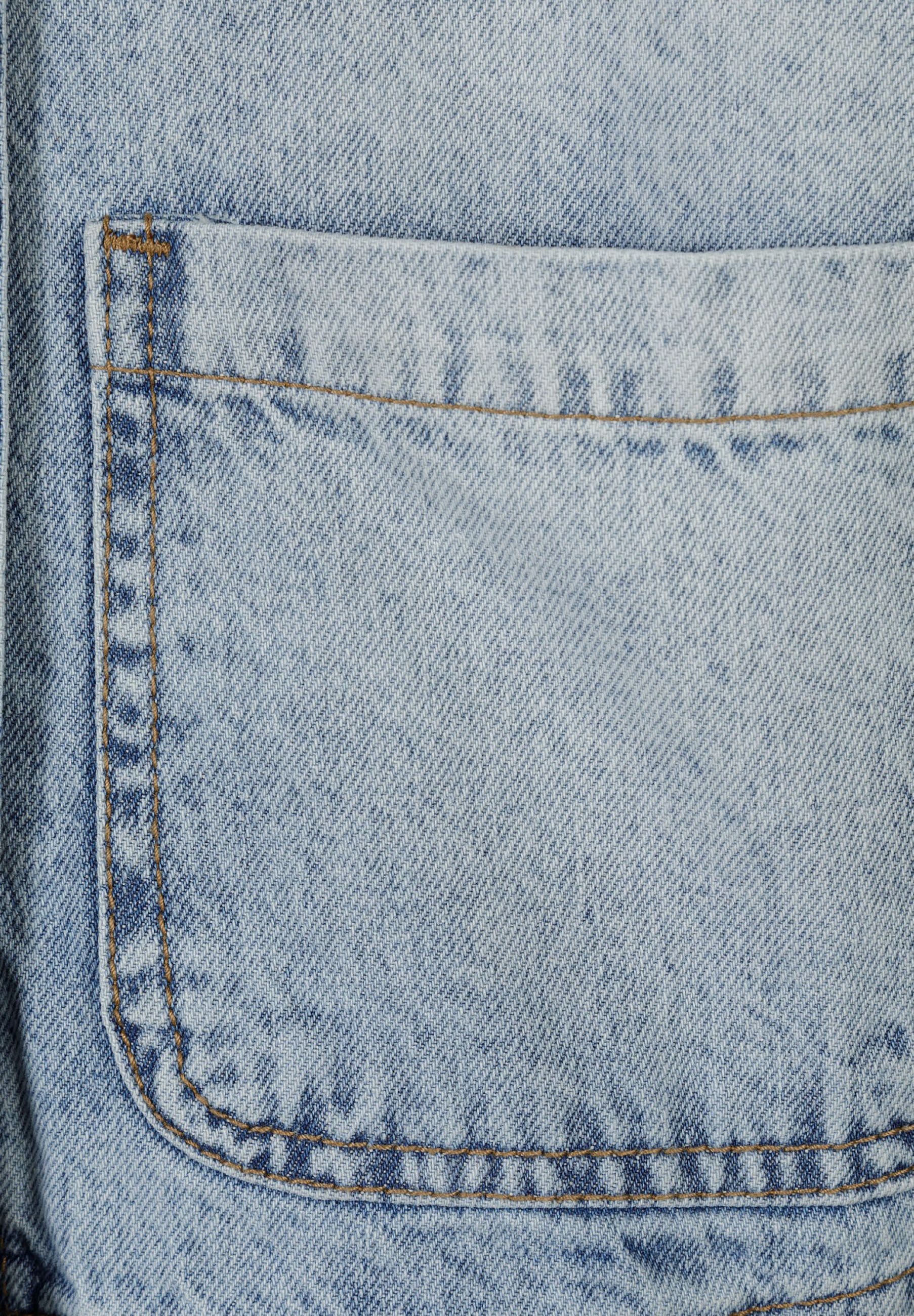 Detail of a light blue oversized denim jacket featuring a patch pocket.