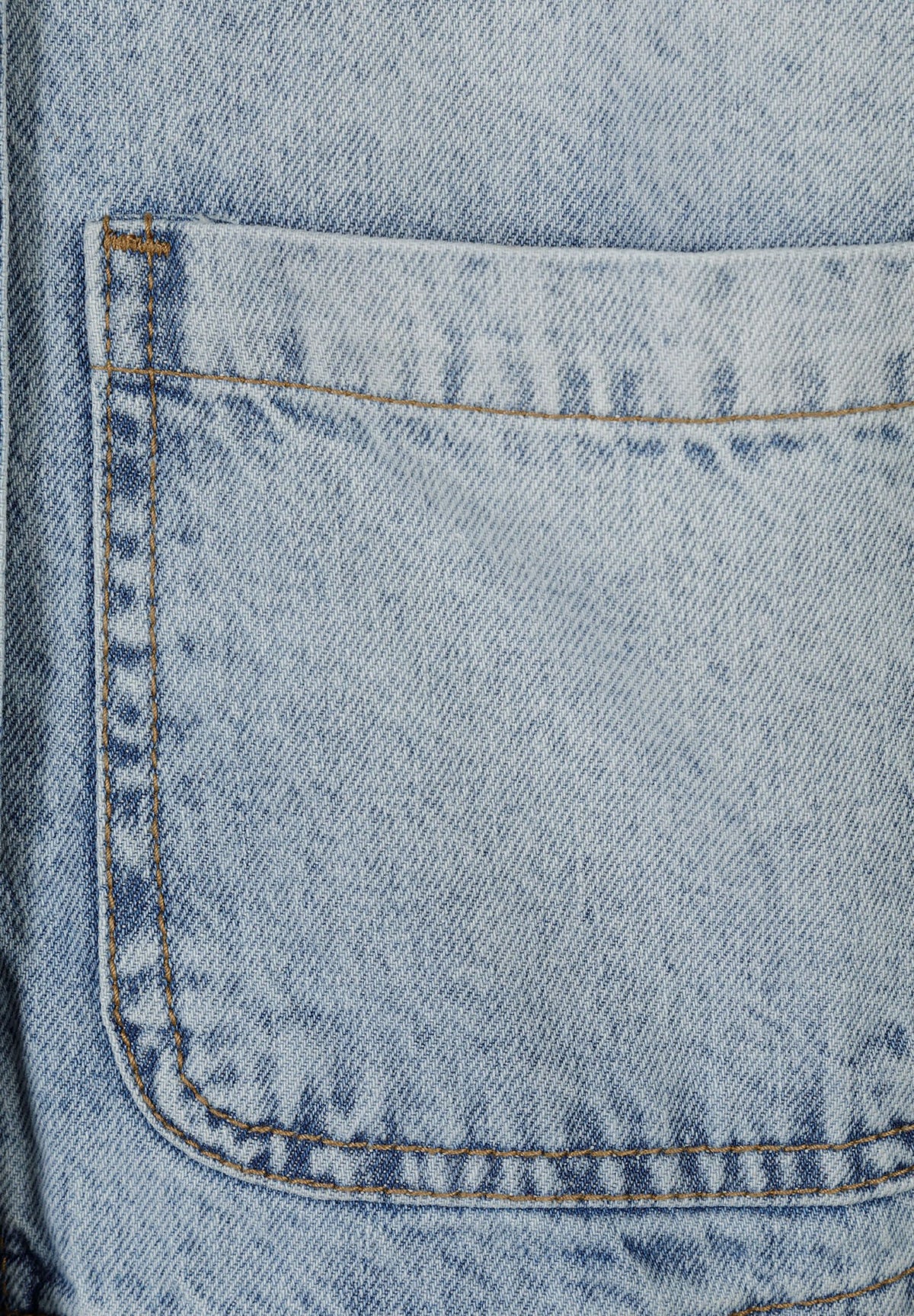 Close-up of a large stitched patch pocket on the light wash blue denim jacket.