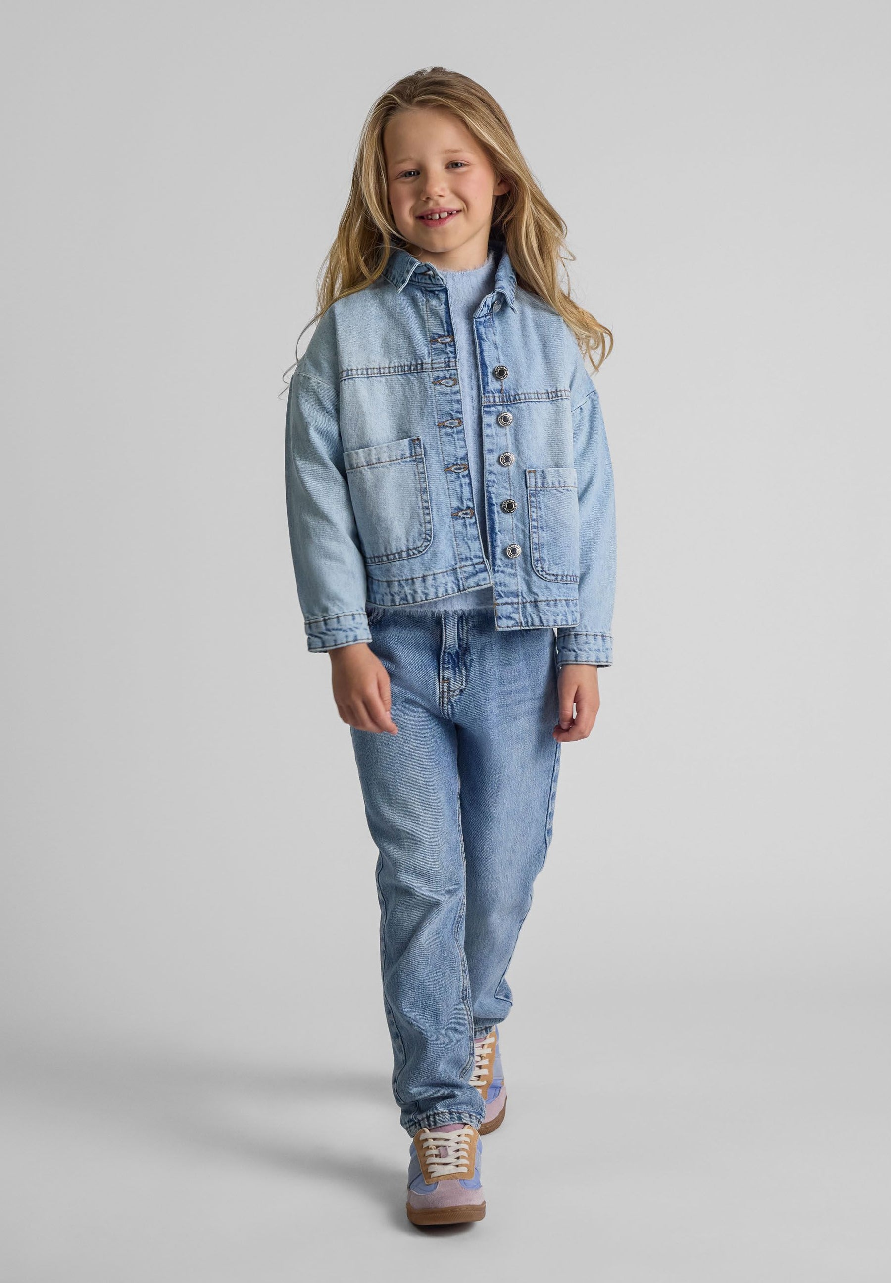 Girls oversized light blue denim jacket, front view with two patch pockets.