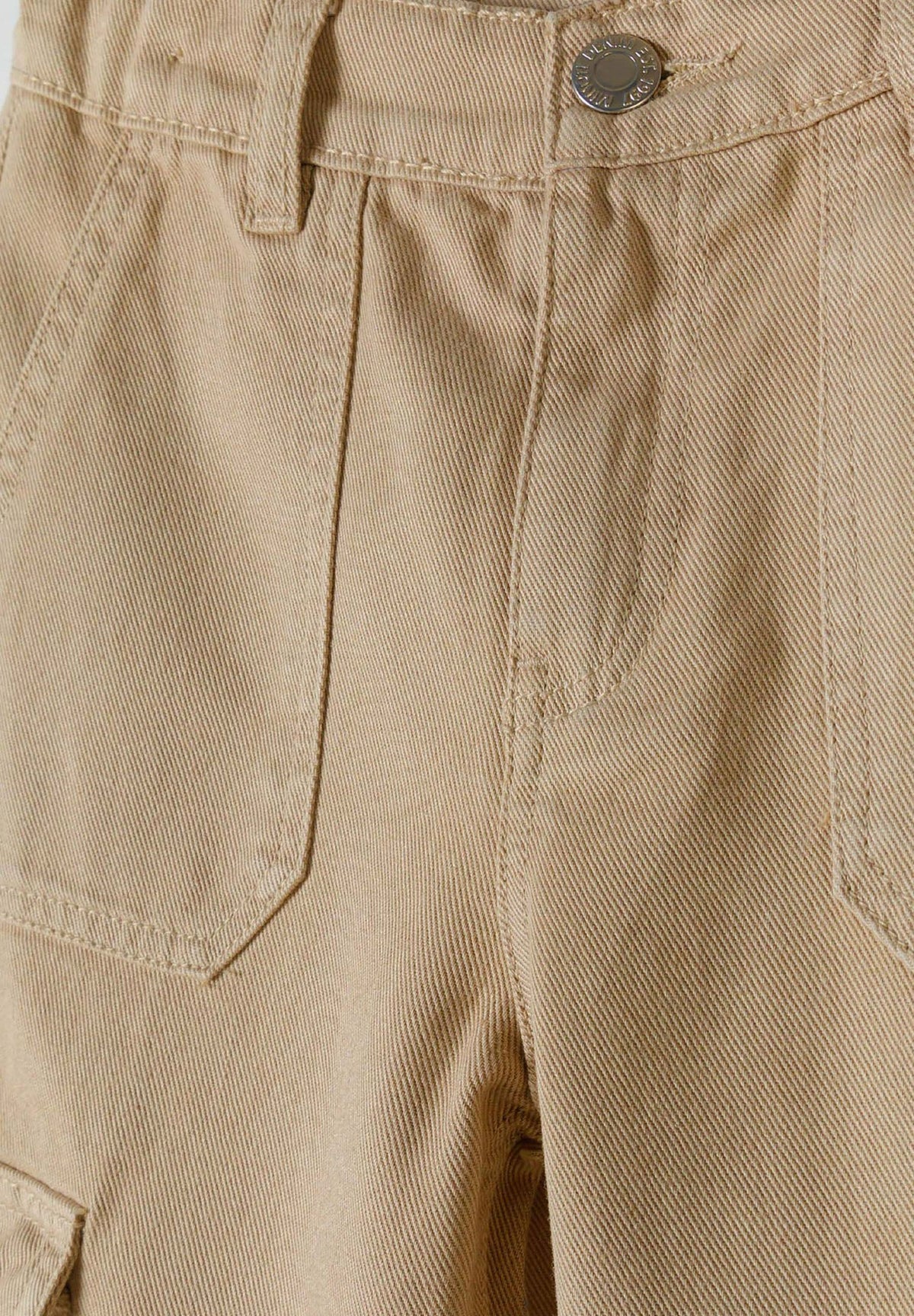 Close-up of beige cargo trouser button waist, belt loop and angular front patch pockets.